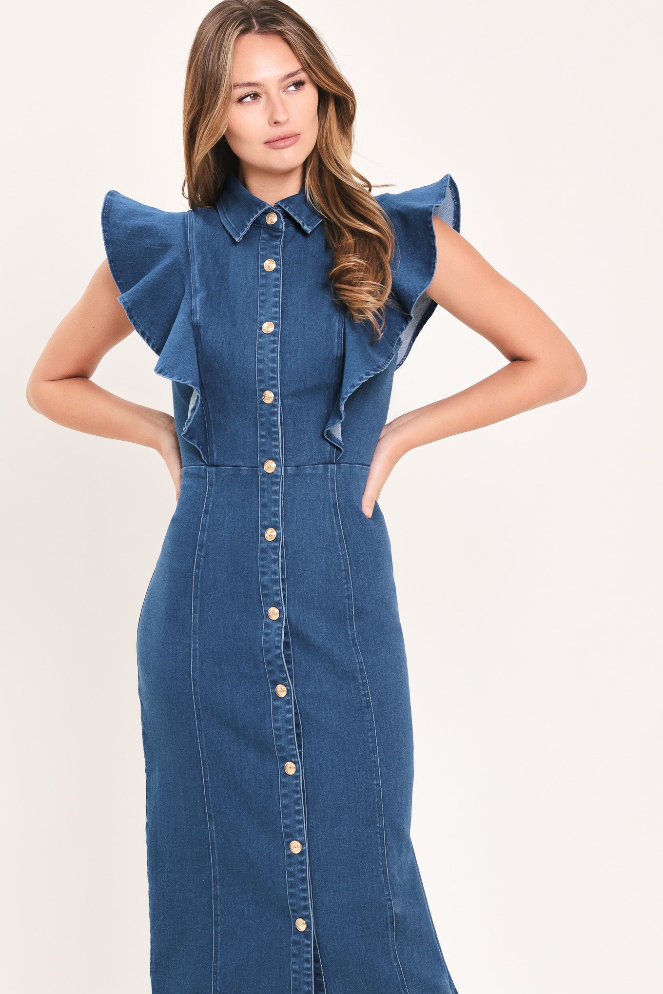 A woman wearing a blue denim midi dress with ruffled cap sleeves, a button-down front, and a pointed collar | Flying Tomato