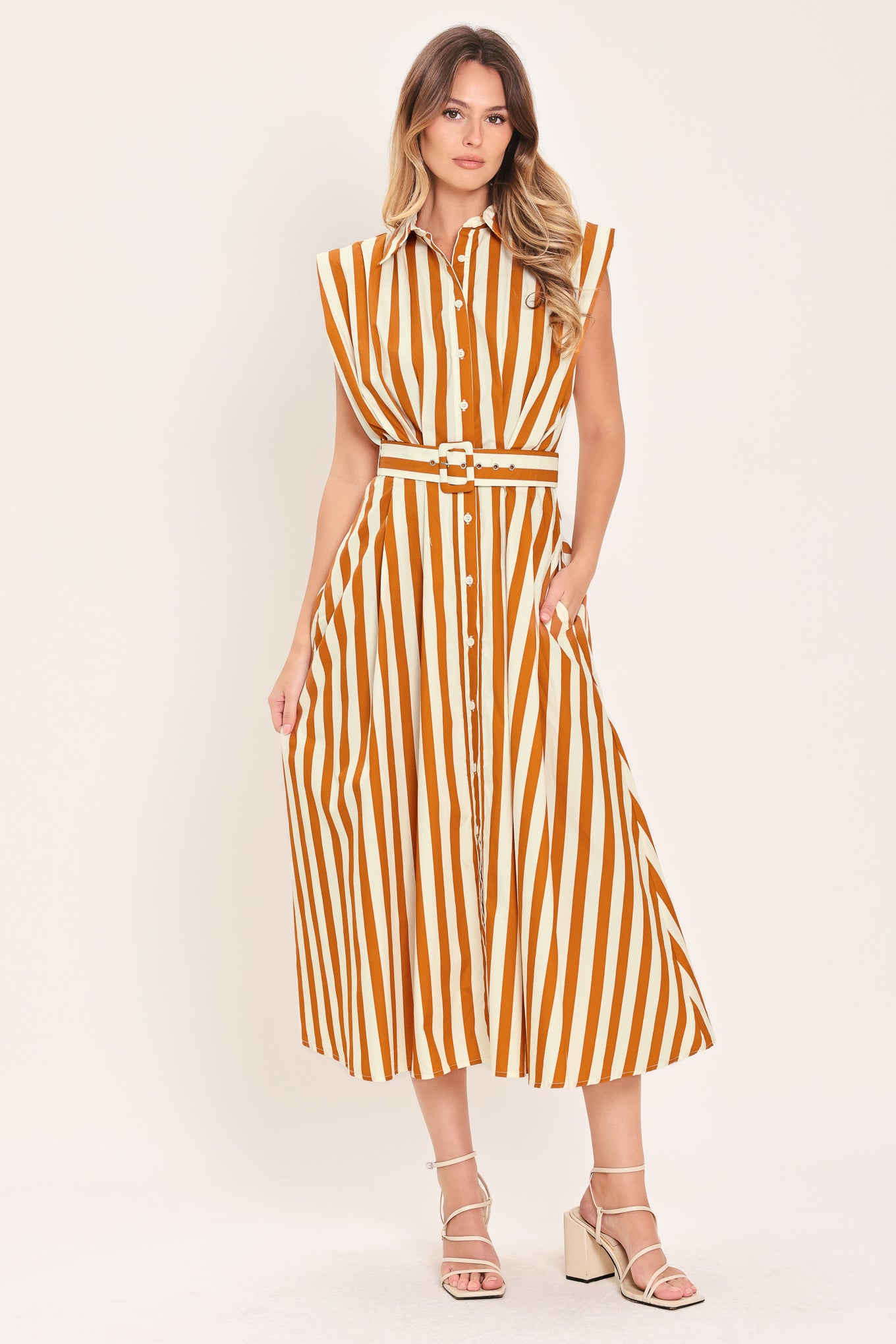 Woman wearing a sleeveless caramel and white striped dress with a belt | Flying Tomato