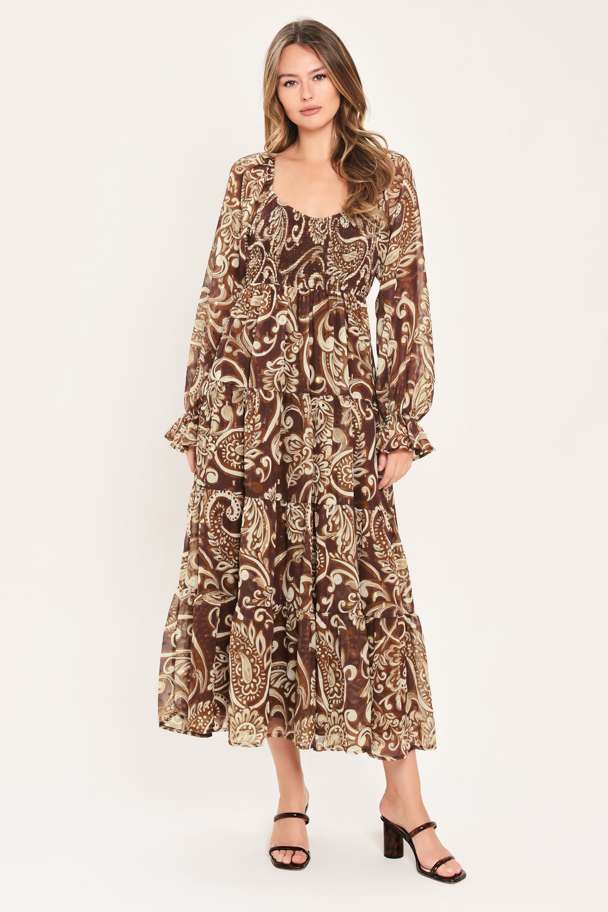A woman wearing a long-sleeved midi dress with a brown and beige paisley pattern | Flying Tomato
