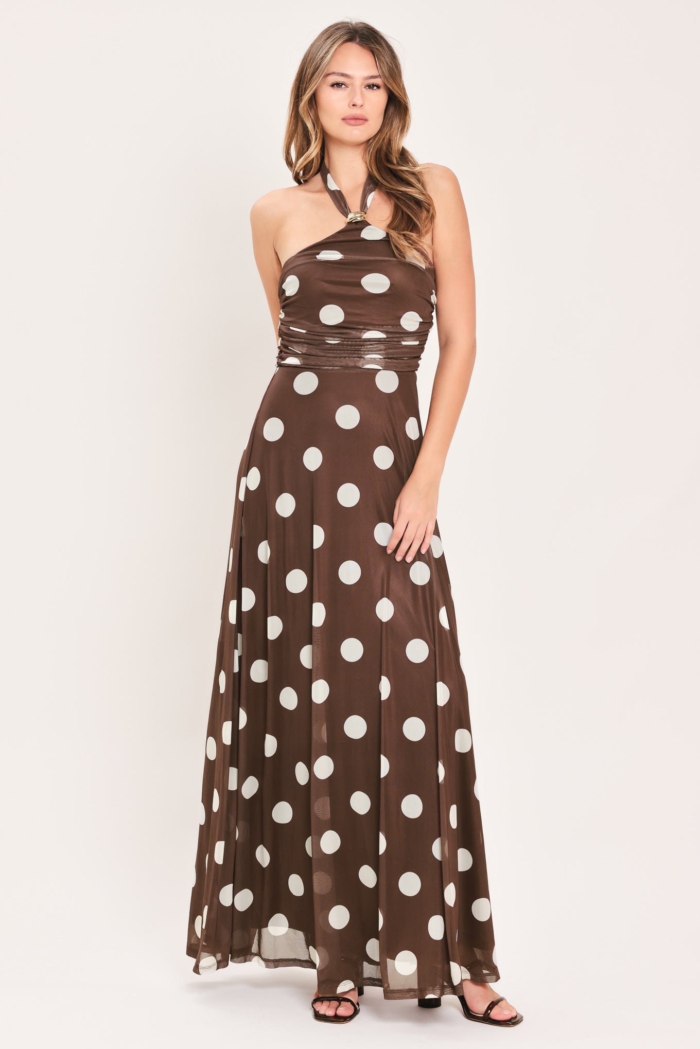 A woman modeling a brown halter-neck maxi dress with a white polka dot pattern | Flying Tomato