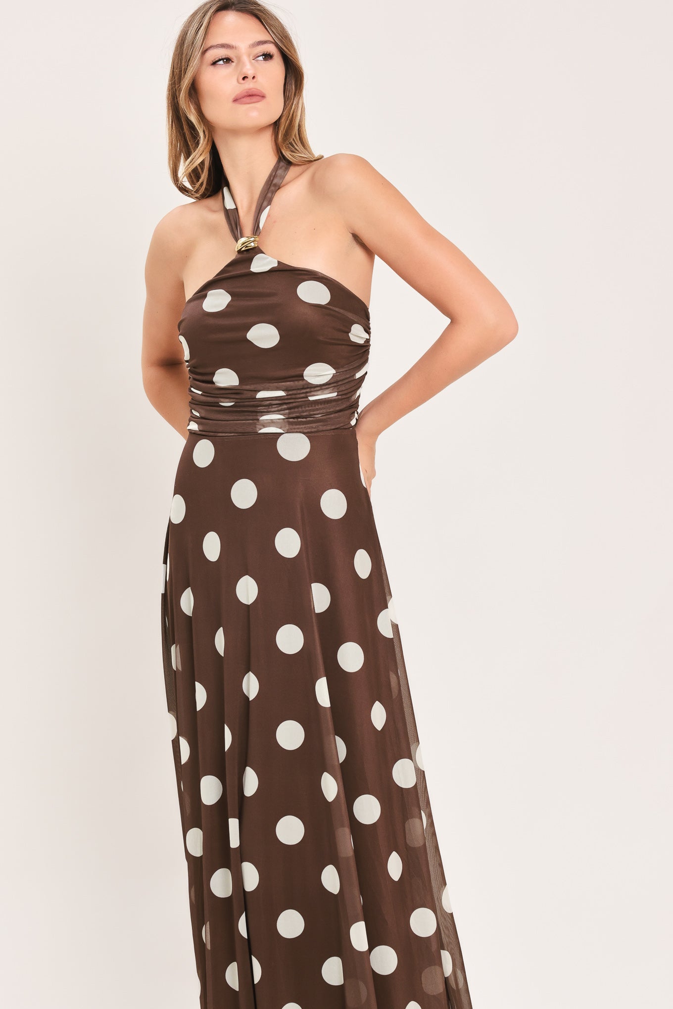 A woman modeling a brown halter-neck maxi dress with a white polka dot pattern | Flying Tomato
