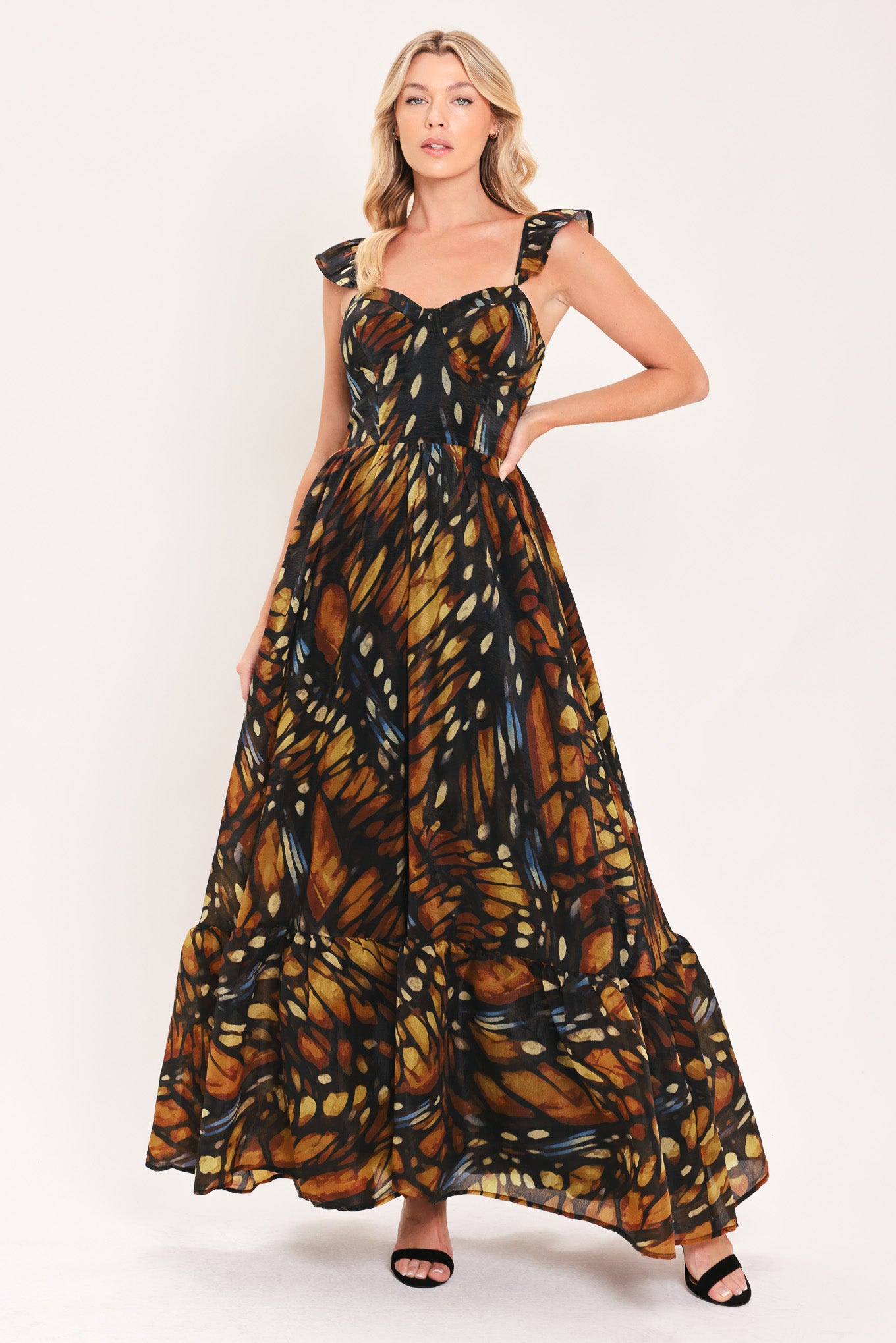 A woman modeling a maxi sleeveless dress with a butterfly wing print in orange, brown, black, and beige tones | Flying Tomato