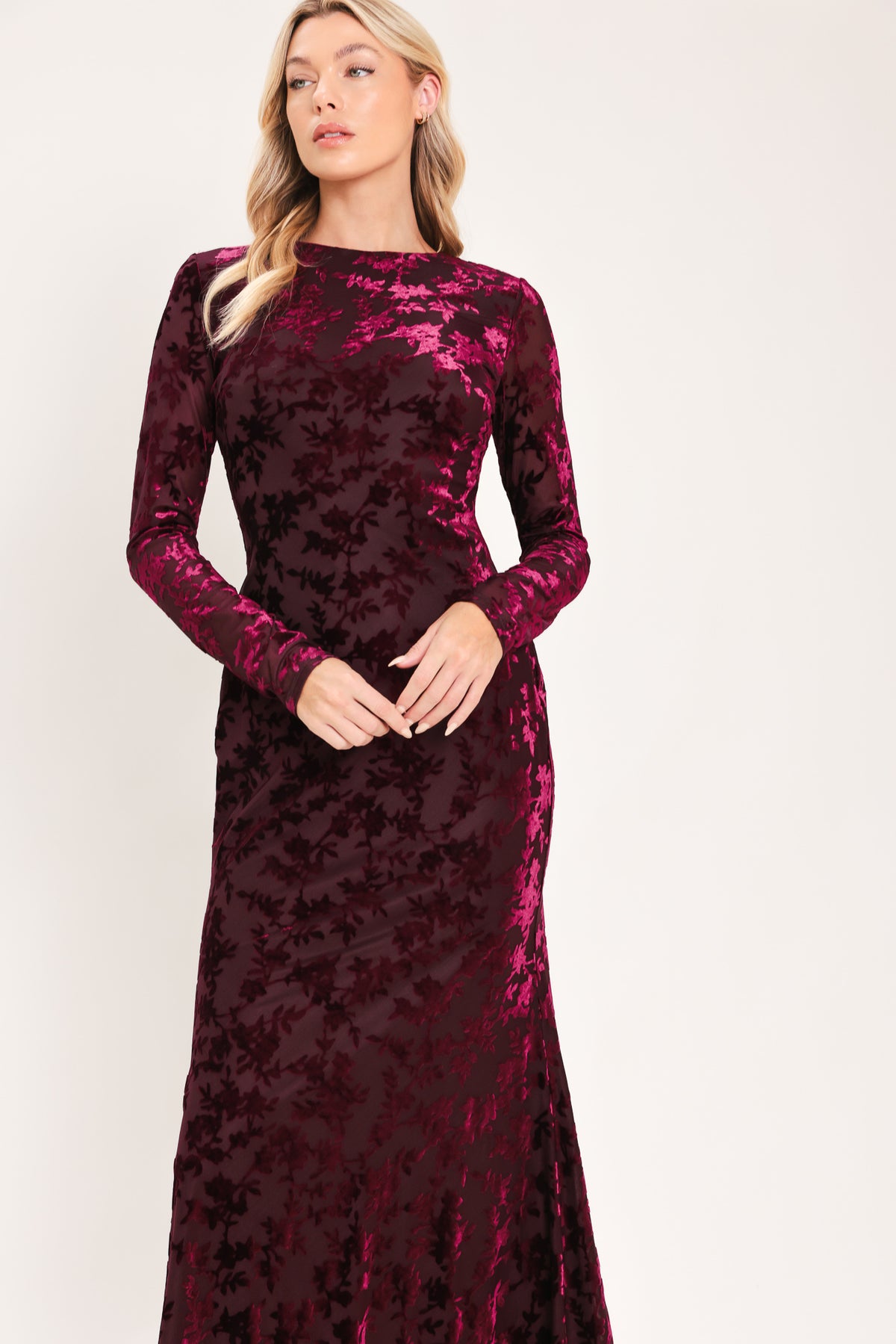 A woman modeling a long-sleeve, midi burgundy velvet dress with an allover tonal floral jacquard pattern | Flying Tomato