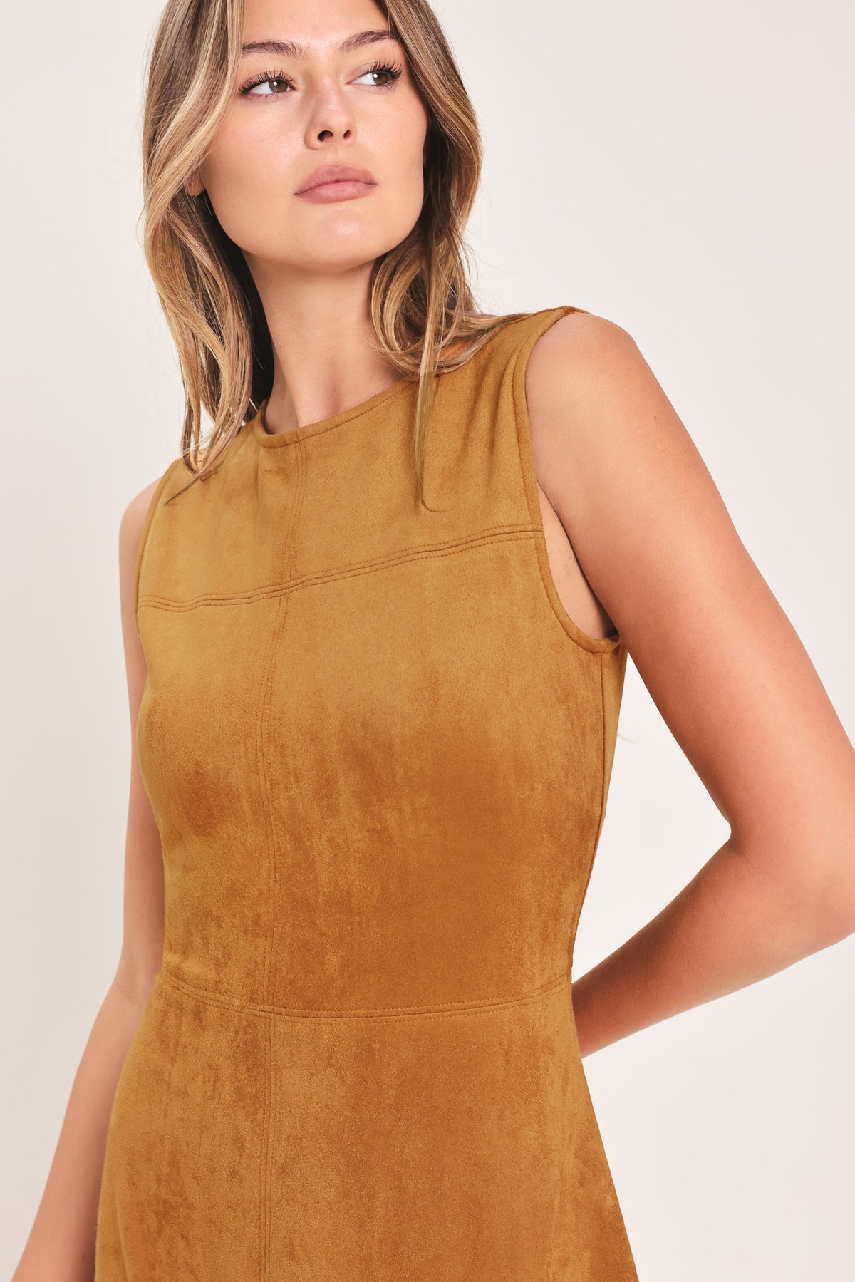 A woman modeling a sleeveless, high-neck, midi-length camel brown dress with a flared skirt | Flying Tomato