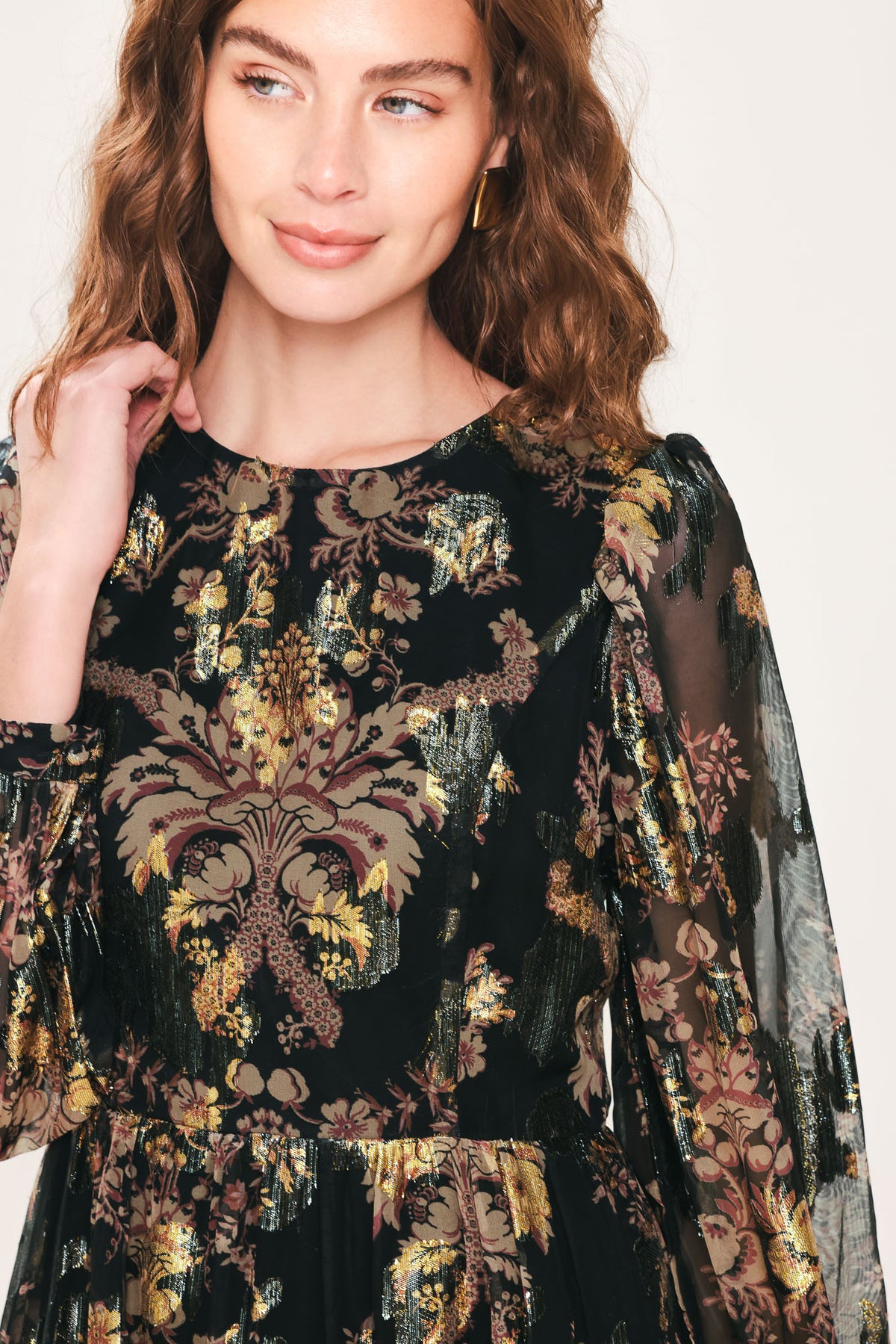 Woman wearing a black long sleeve mini dress with metallic baroque print and tiered skirt | Flying Tomato