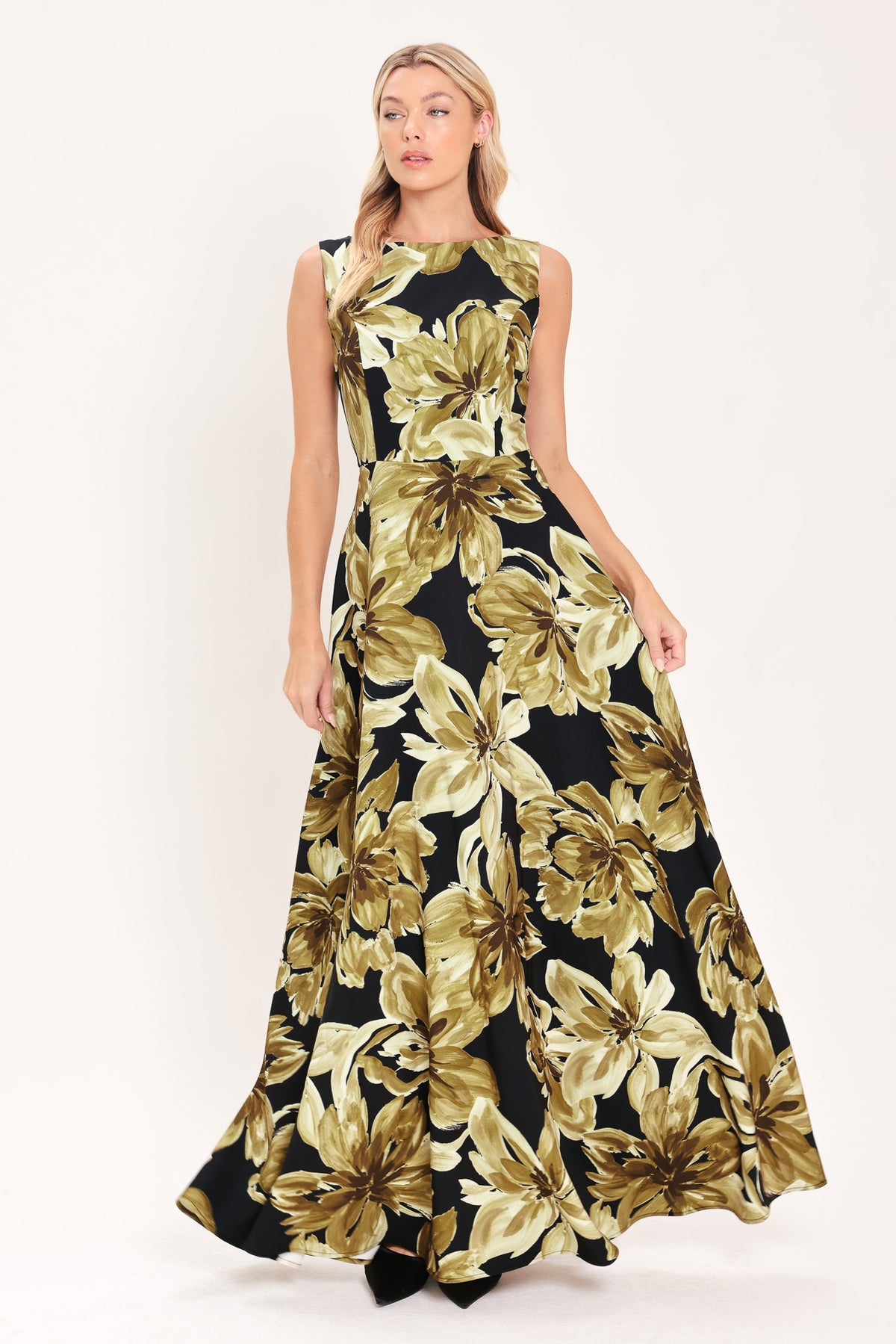 A woman modeling a sleeveless, floor-length maxi dress with a black background and a large gold floral print | Flying Tomato