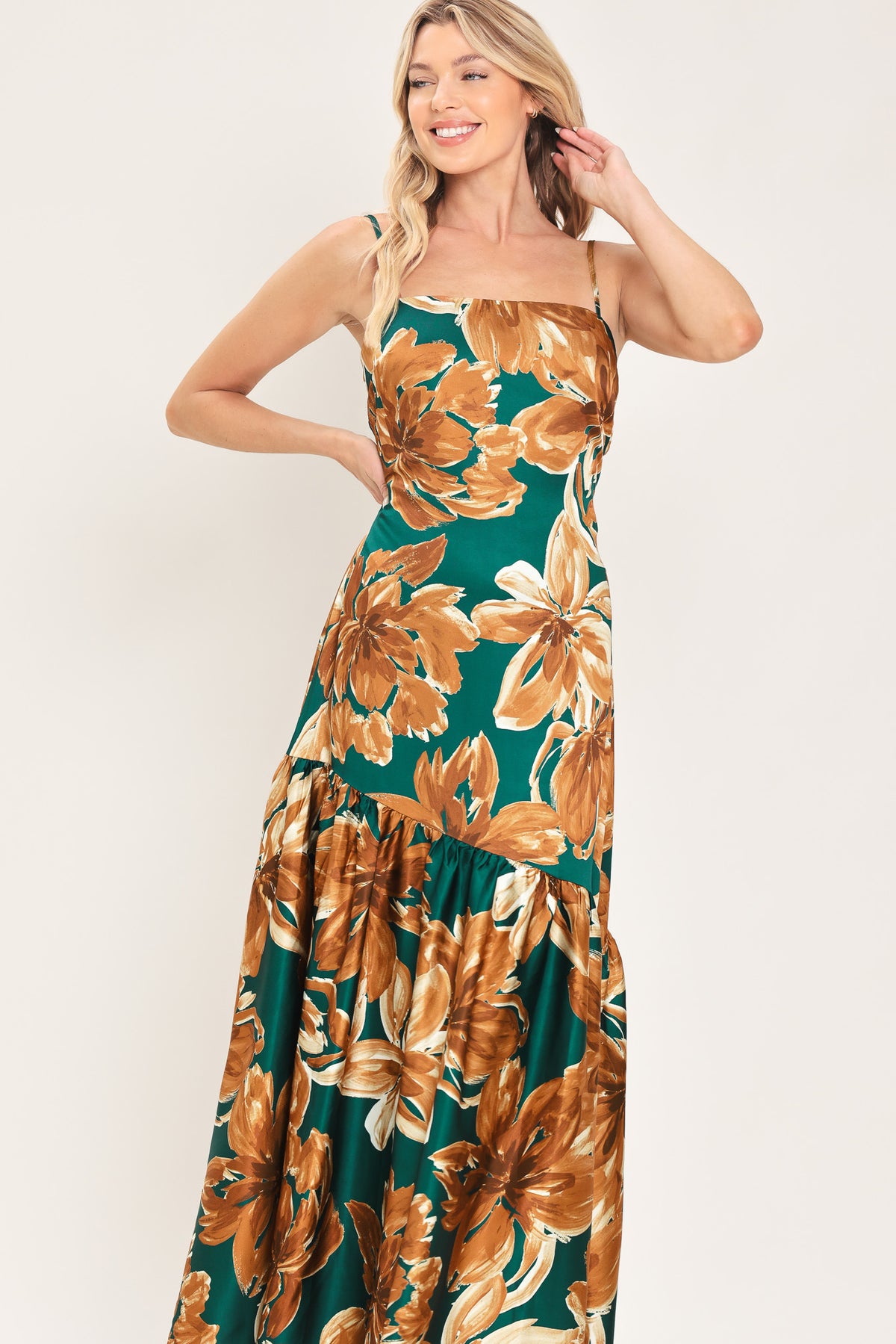 Woman wearing a spaghetti strap green maxi dress with brown floral pattern printed and asymmetrical tier from the thigh down | Flying Tomato