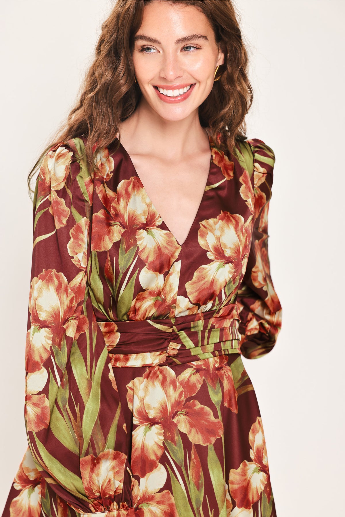 Woman wearing a burgundy long sleeve mini dress with a v neckline and ruched waist and floral and leaf print | Flying Tomato