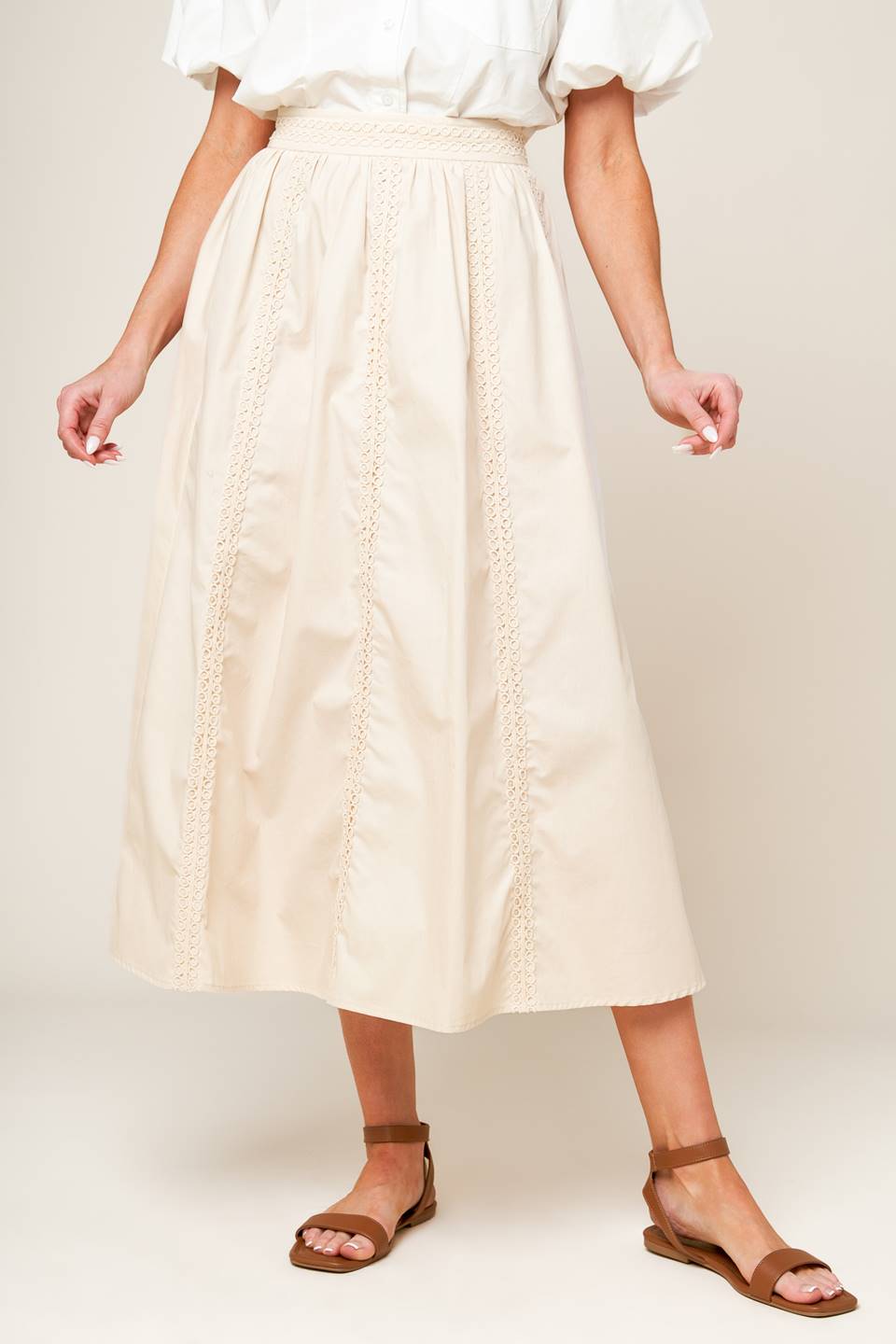 A solid woven midi skirt with lace trim detail and side zipper closure.