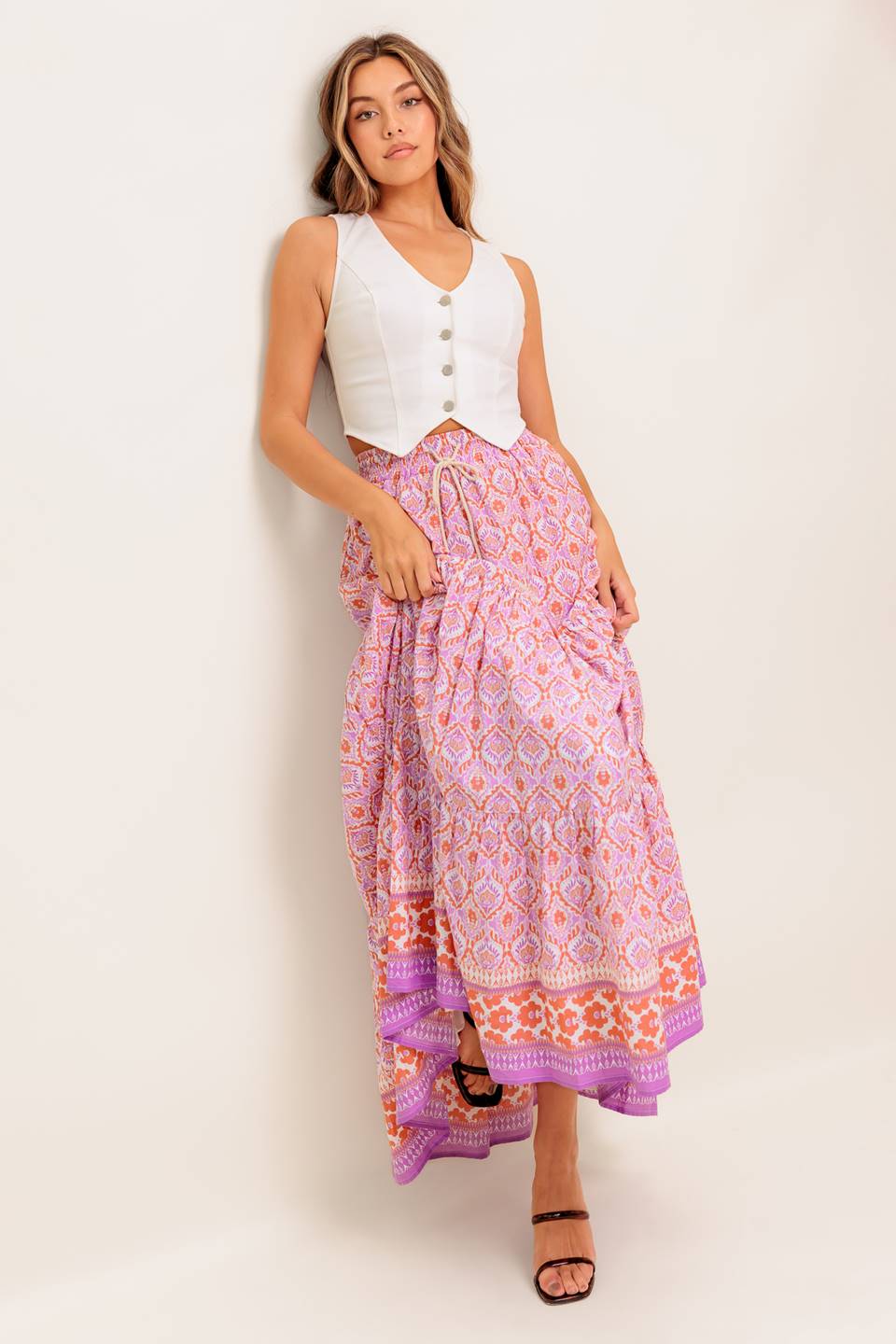 A printed woven maxi skirt featuring elasticized waist with contrasting tie and tiered bottom.