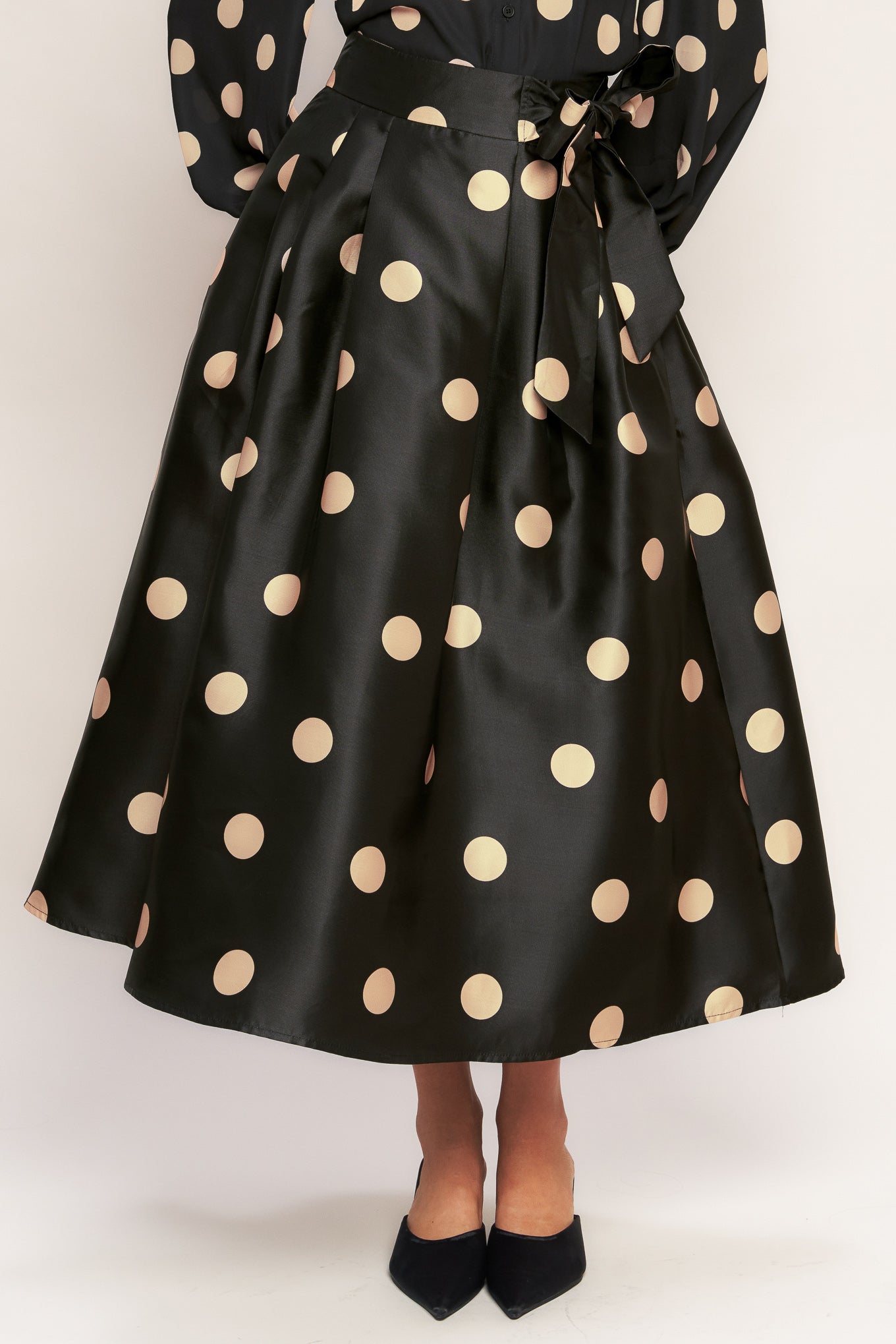 A polka-dotted printed woven full midi skirt featuring side zipper closure with tie.