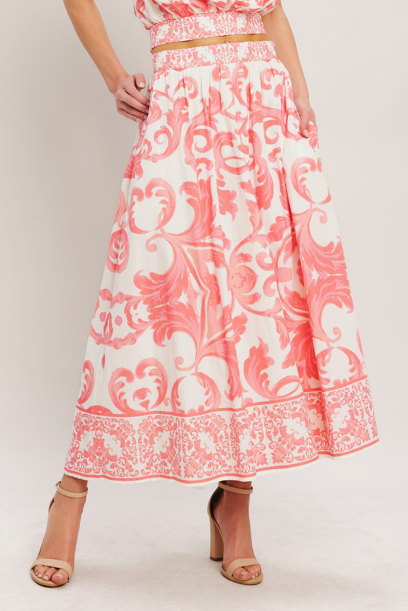 Coral and white patterned skirt worn by a person on a plain background