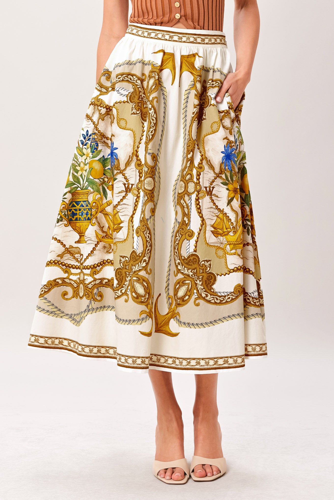 Woman wearing a midi skirt with intricate gold and multicolor pattern and side zipper closure | Flying Tomato