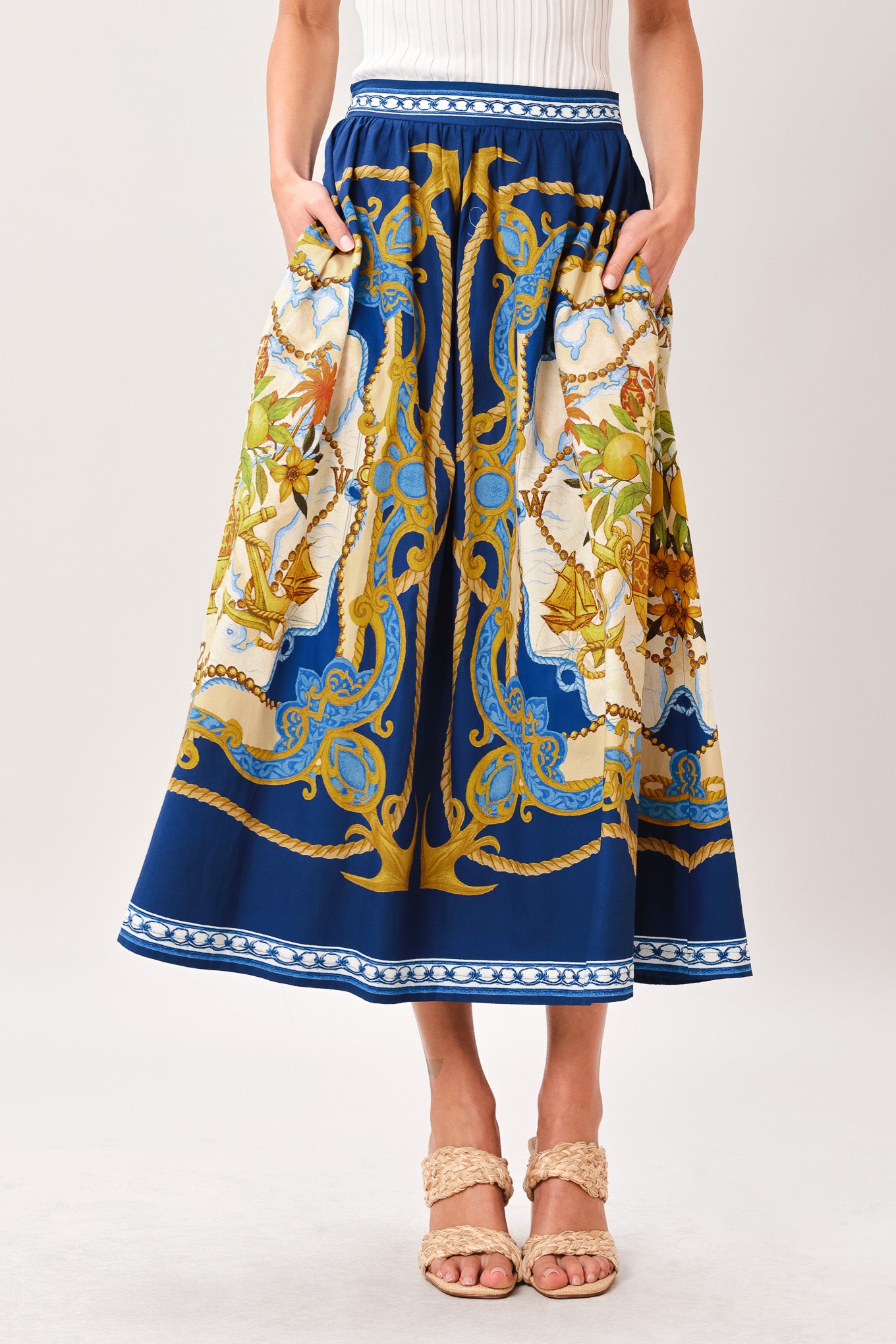 Woman wearing a midi skirt with intricate blue, gold and multicolor pattern and side zipper closure | Flying Tomato