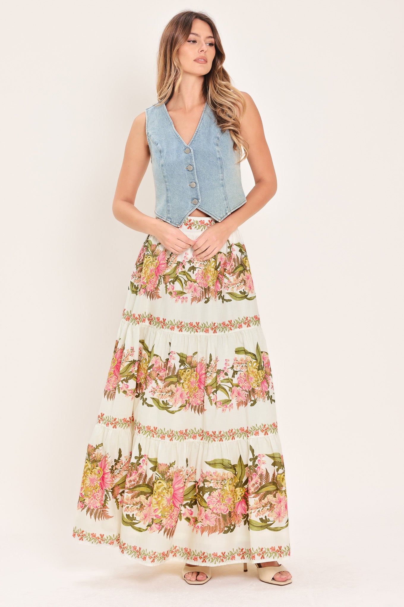 Woman wearing a pink, green and white floral print woven maxi skirt with tiers and smocked back waistband | Flying Tomato