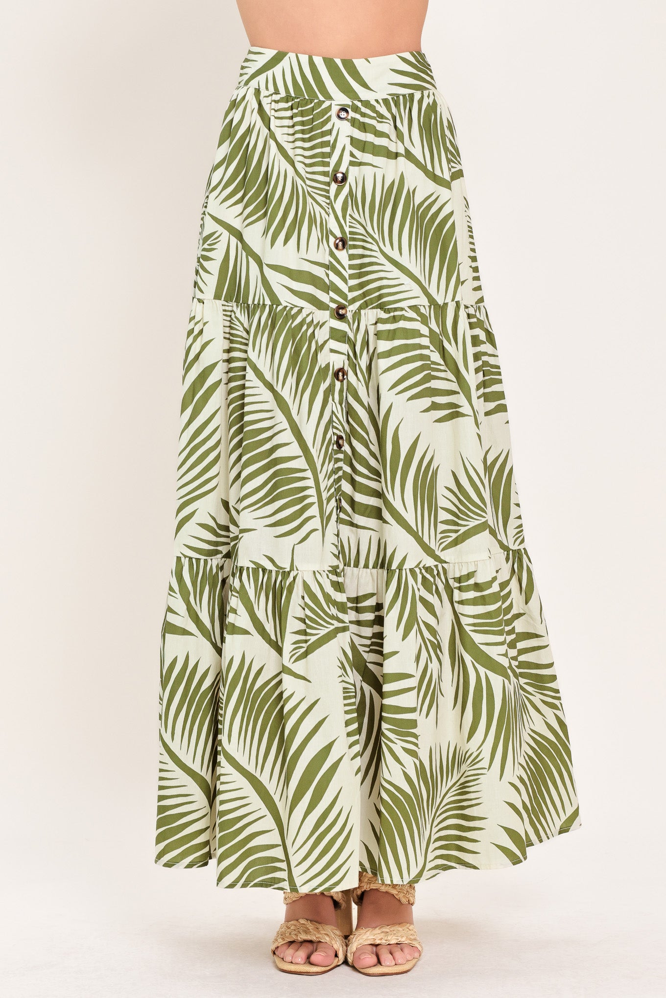 Woman wearing a green leaf-patterned maxi skirt featuring front button down, tiers and smocked back waistband | Flying Tomato