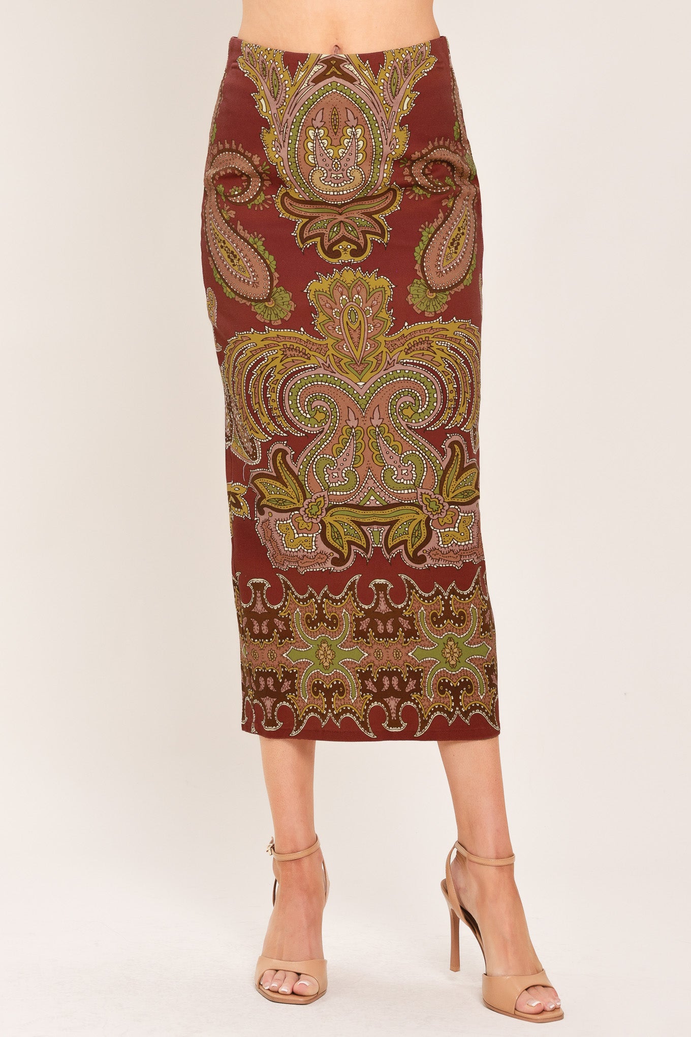 A woman wearing a midi skirt with an ornate paisley pattern in rust red, gold, and olive green | Flying Tomato