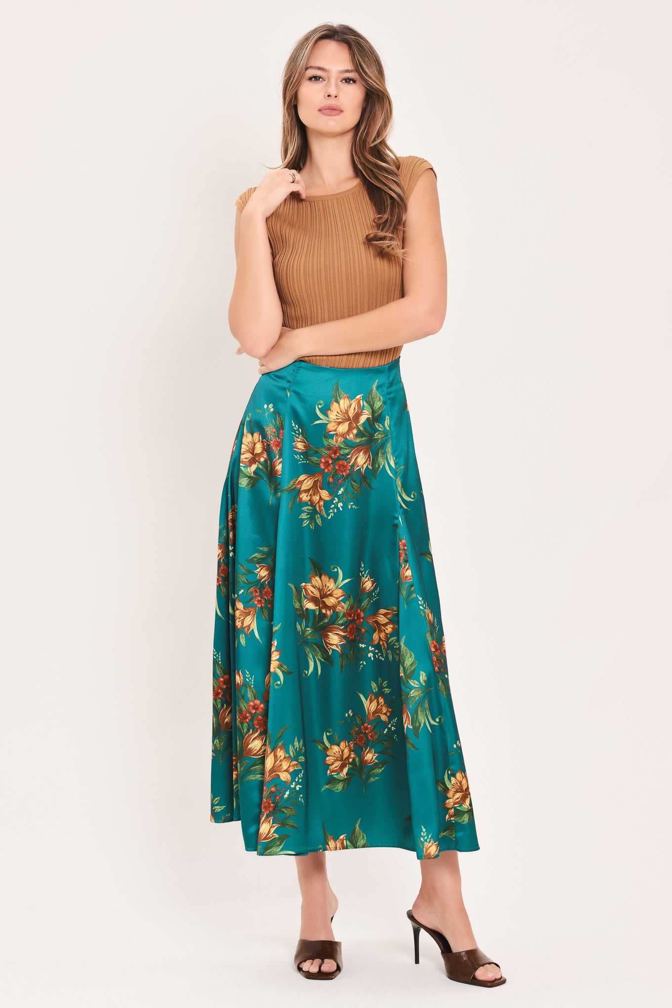 A woman wearing a teal green midi skirt with a vibrant orange and yellow floral print | Flying Tomato