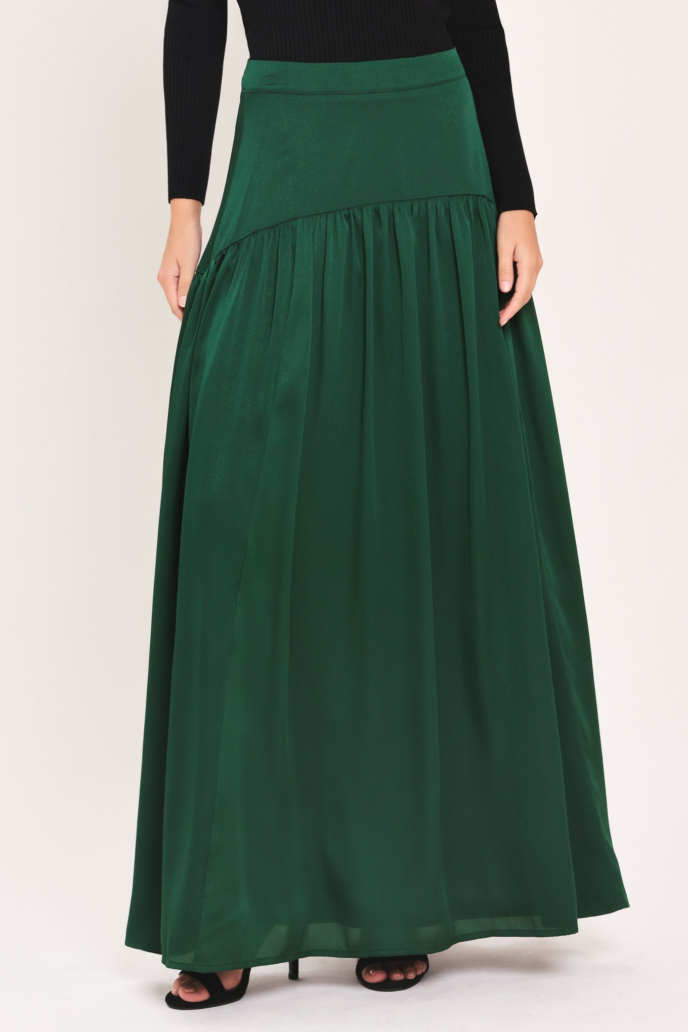 A dark hunter green satin-like maxi skirt with a drop waist worn by a model | Flying Tomato