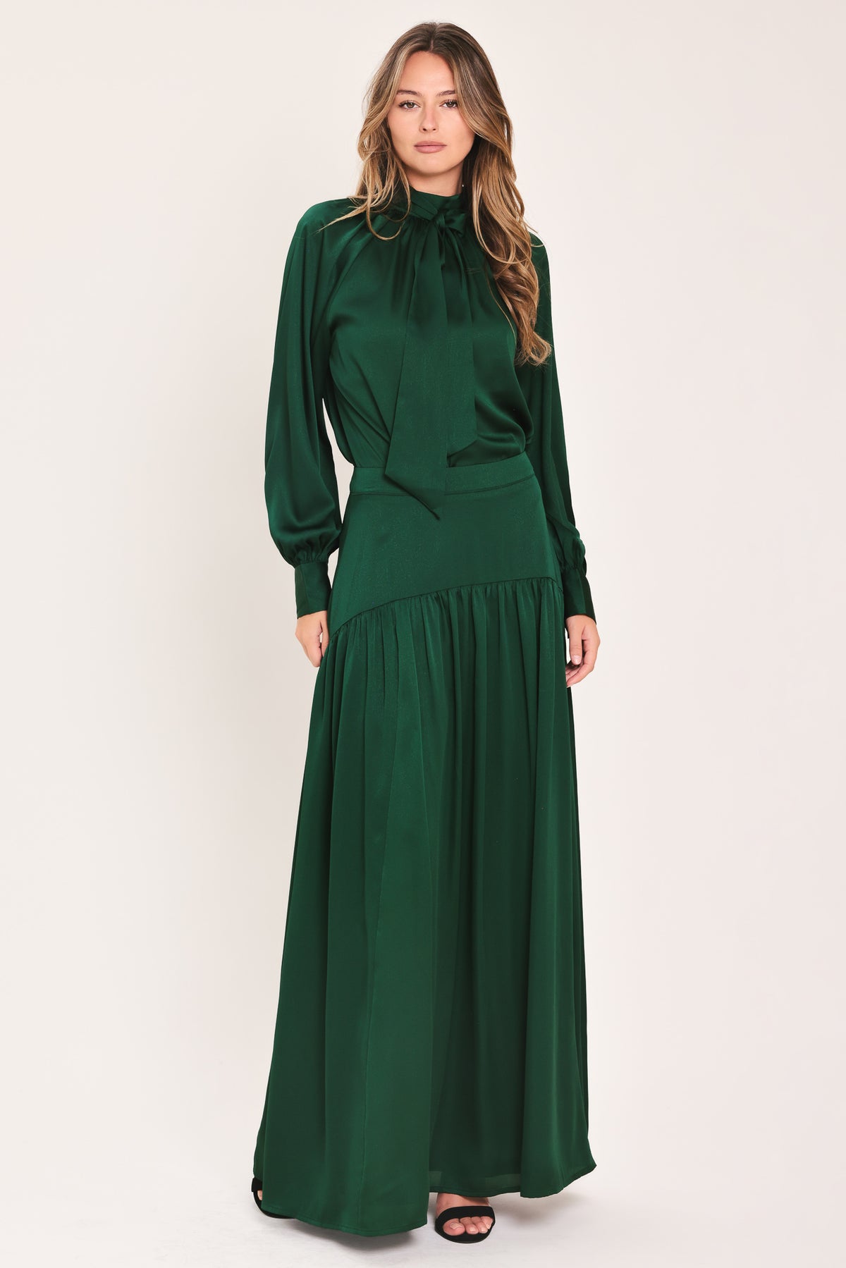 A dark hunter green satin-like maxi skirt with a drop waist worn by a model | Flying Tomato