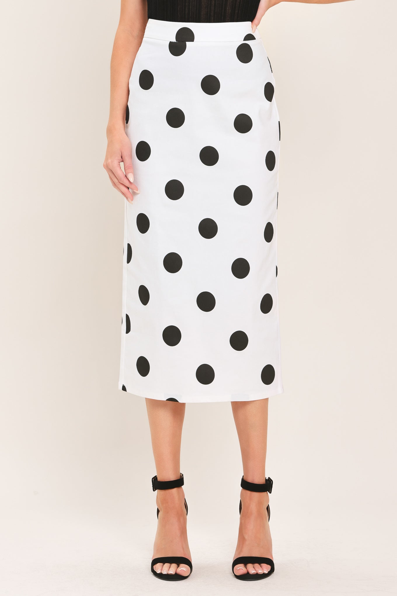 A woman wearing a white midi pencil skirt with large black polka dots | Flying Tomato