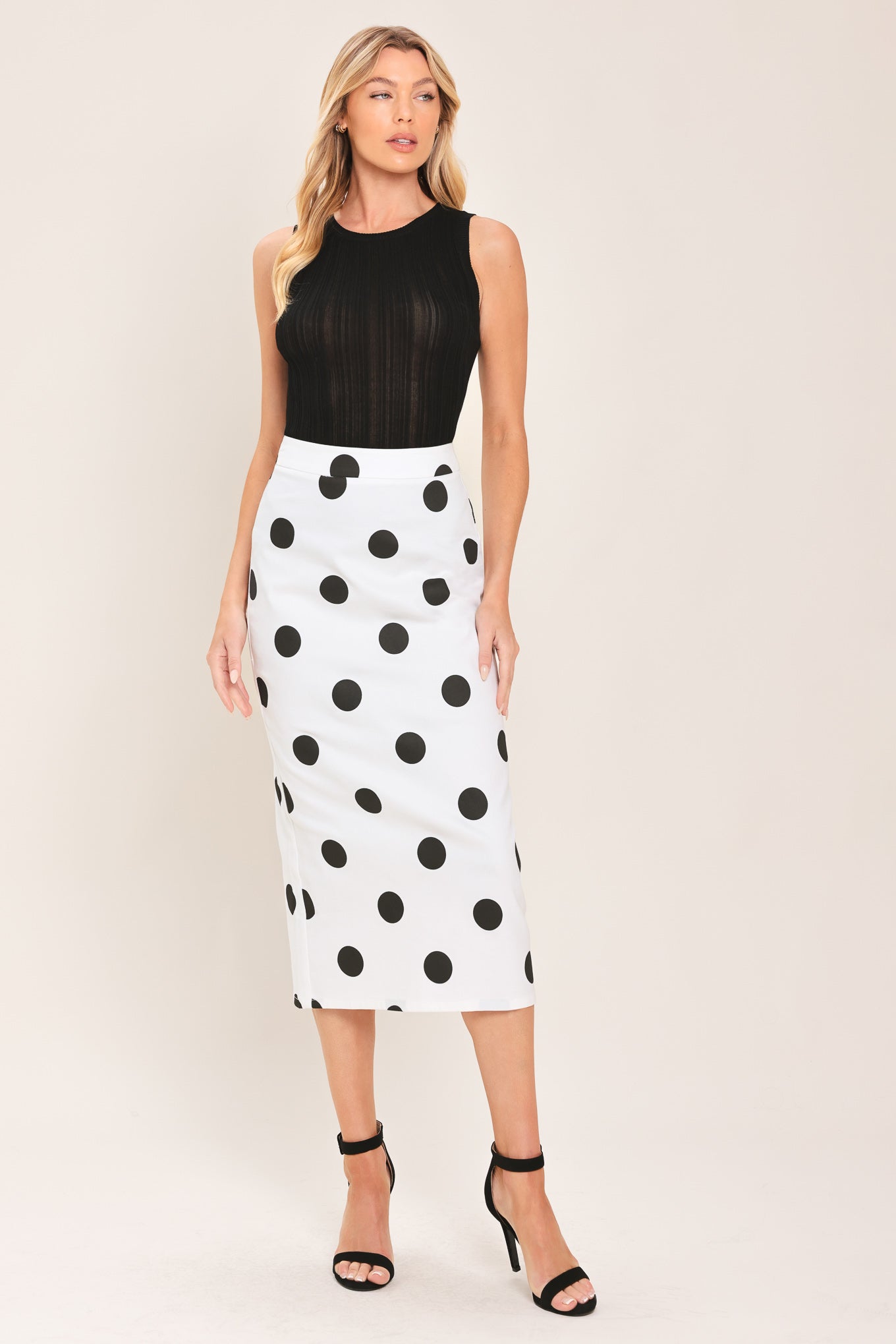 A woman wearing a white midi pencil skirt with large black polka dots | Flying Tomato