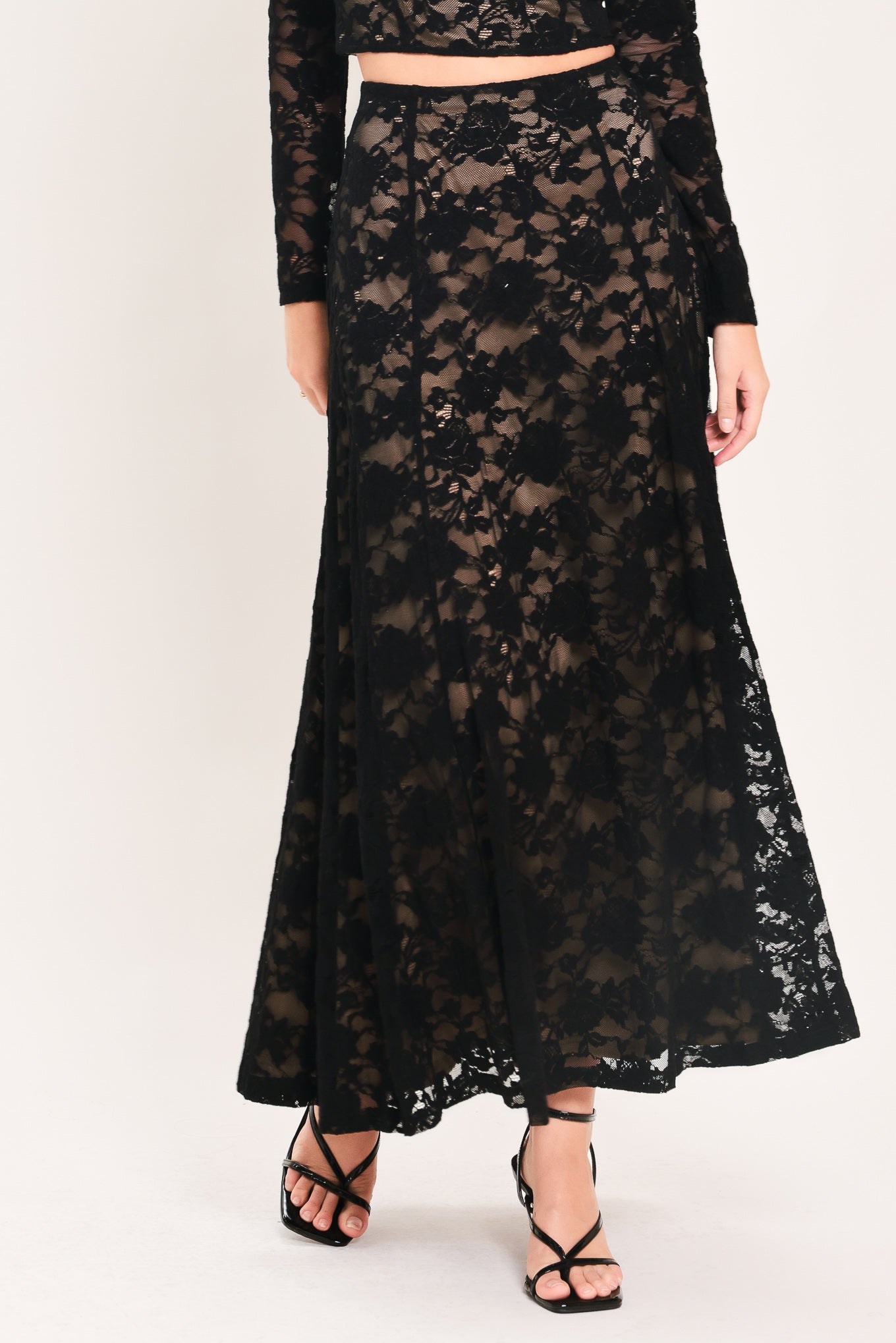 Woman wearing a long black lace skirt with a nude base | Flying Tomato