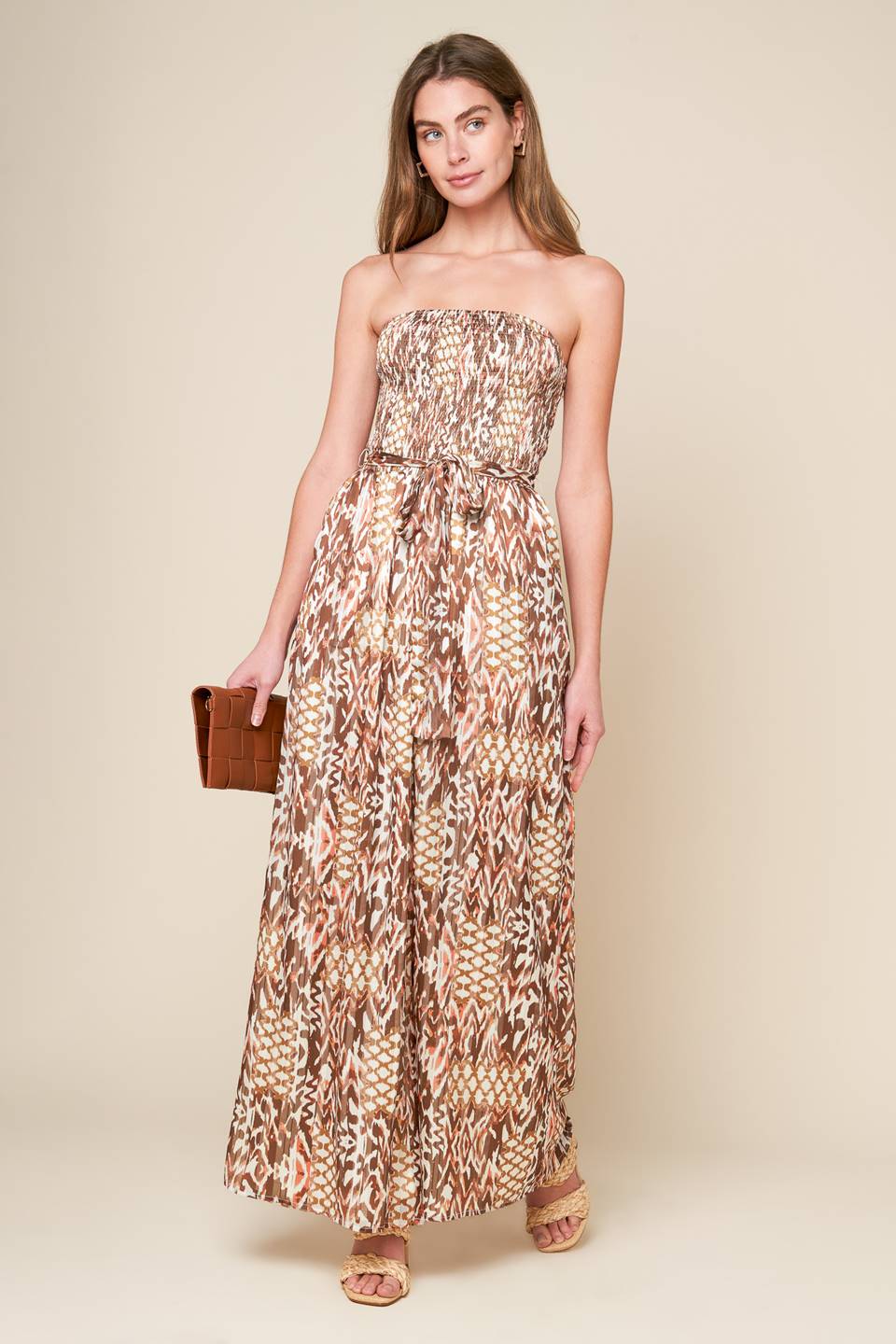 A printed woven jumpsuit with a strapless, smocked bodice, self sash, and wide leg, perfect for a VACAY