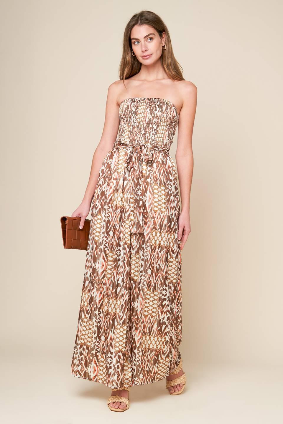 A printed woven jumpsuit with a strapless, smocked bodice, self sash, and wide leg, perfect for a VACAY