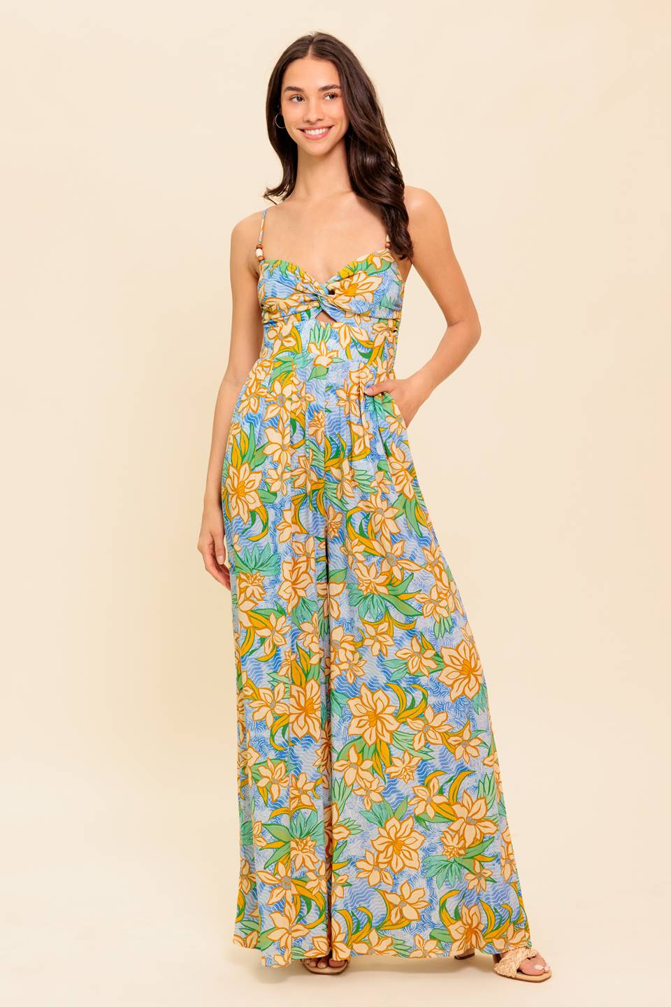 A printed woven jumpsuit featuring twisted bust with cut out, straps with wooden trim, wide leg and smocked back bodice