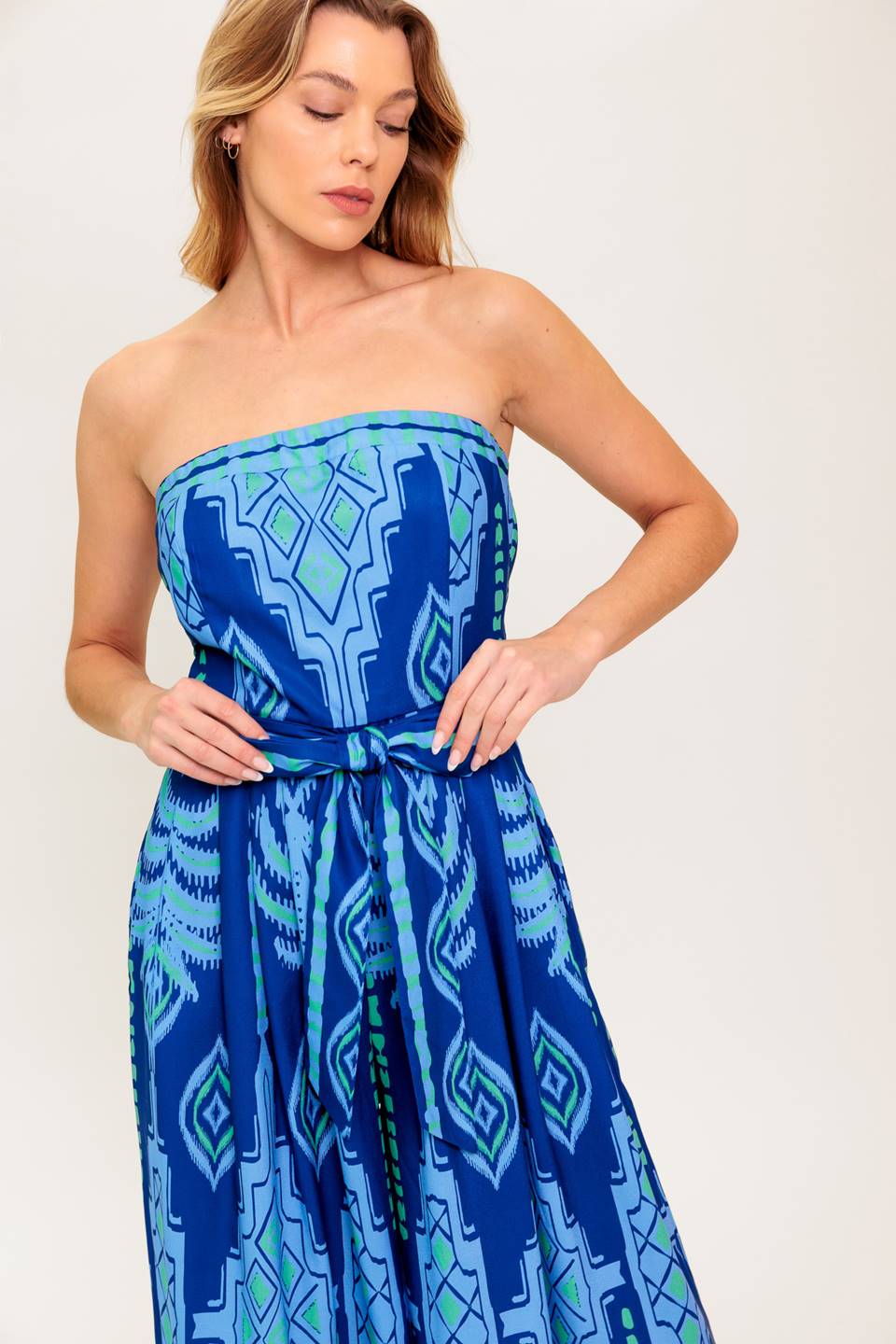 A printed woven jumpsuit featuring strapless, self sash tie, wide leg and back zipper closure