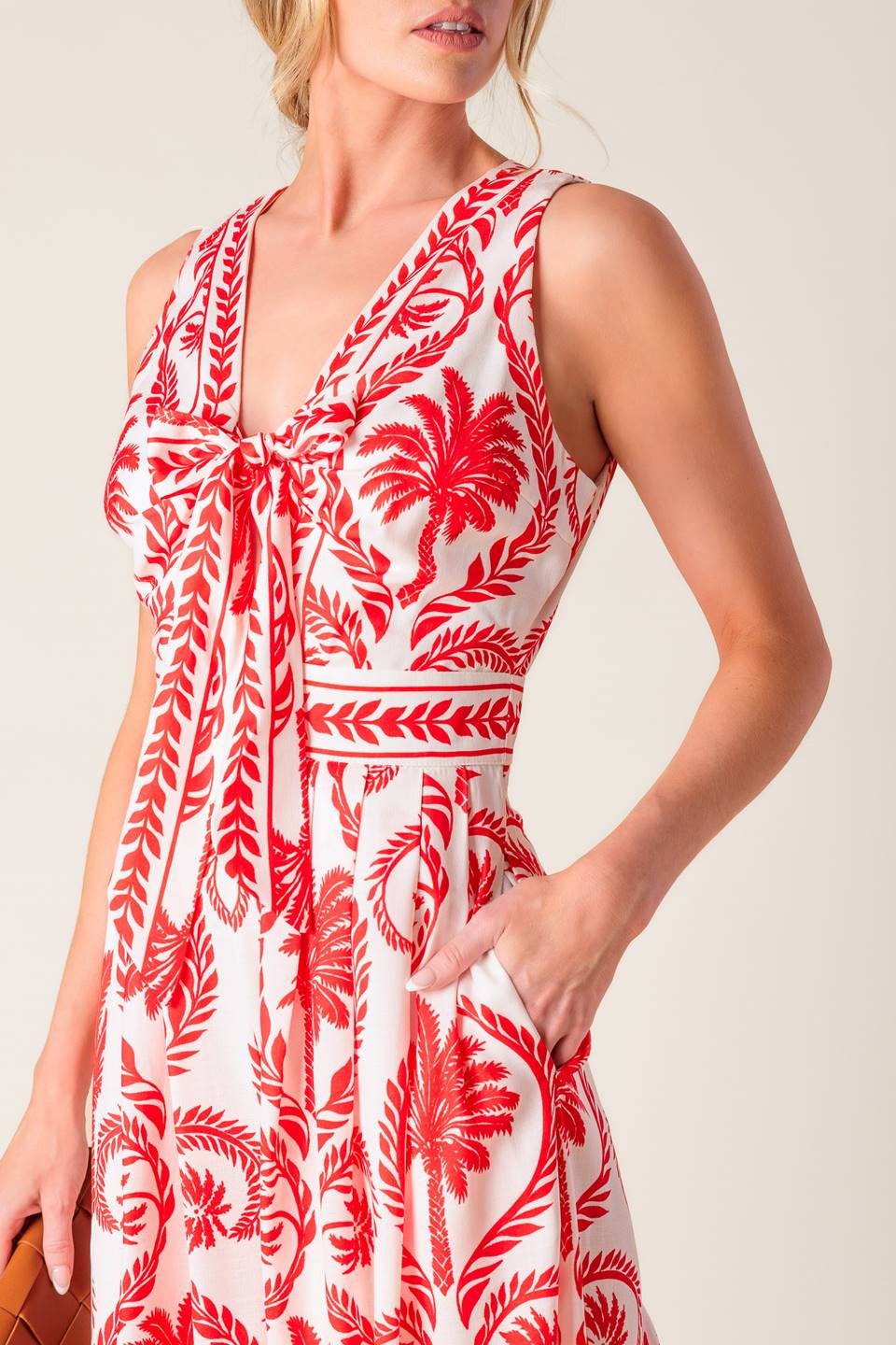 A white and red printed woven jumpsuit featuring V neckline with front tie, sleeveless, wide leg and back zipper closure.
