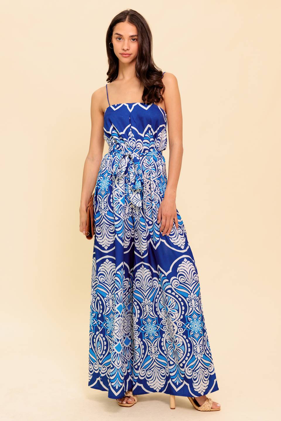 A printed woven jumpsuit featuring straight neckline, skinny straps, self sash belt and wide leg
