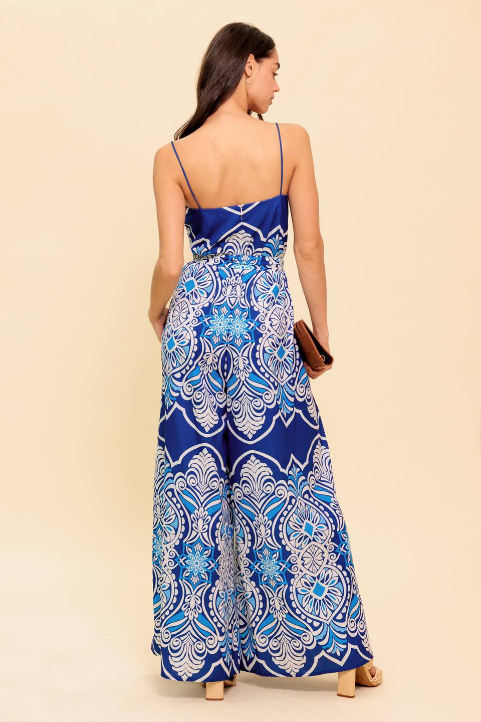 A printed woven jumpsuit featuring straight neckline, skinny straps, self sash belt and wide leg