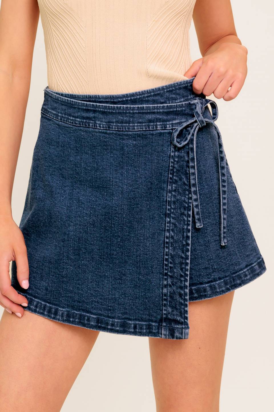 A washed denim skort with side tie and zipper closure.