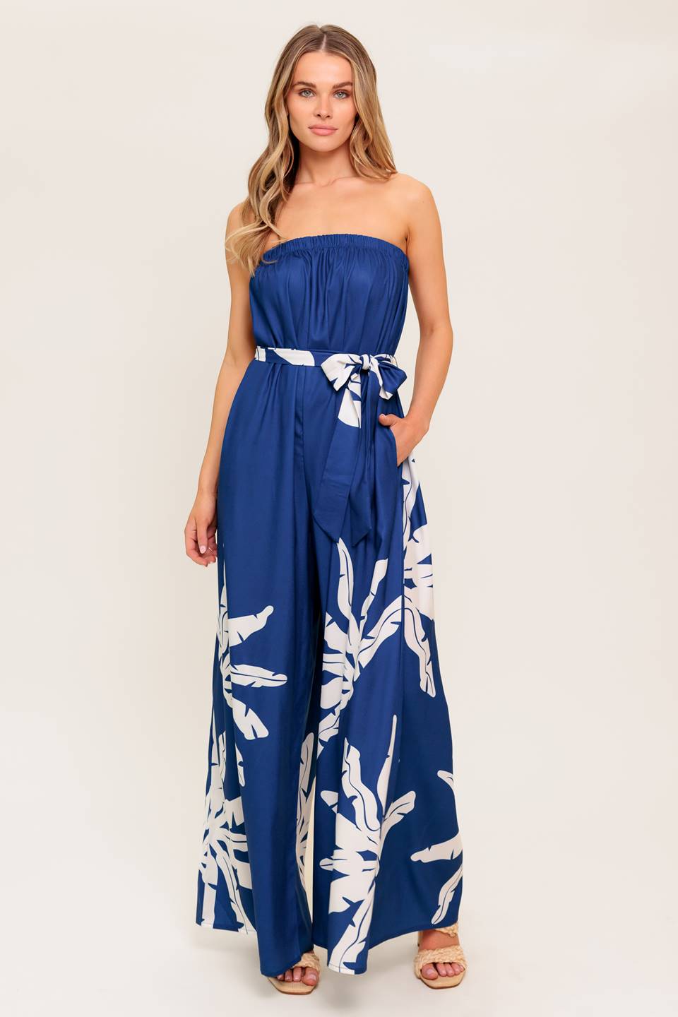 A strapless printed woven jumpsuit featuring an elasticized top opening, self-sash tie, and wide leg.
