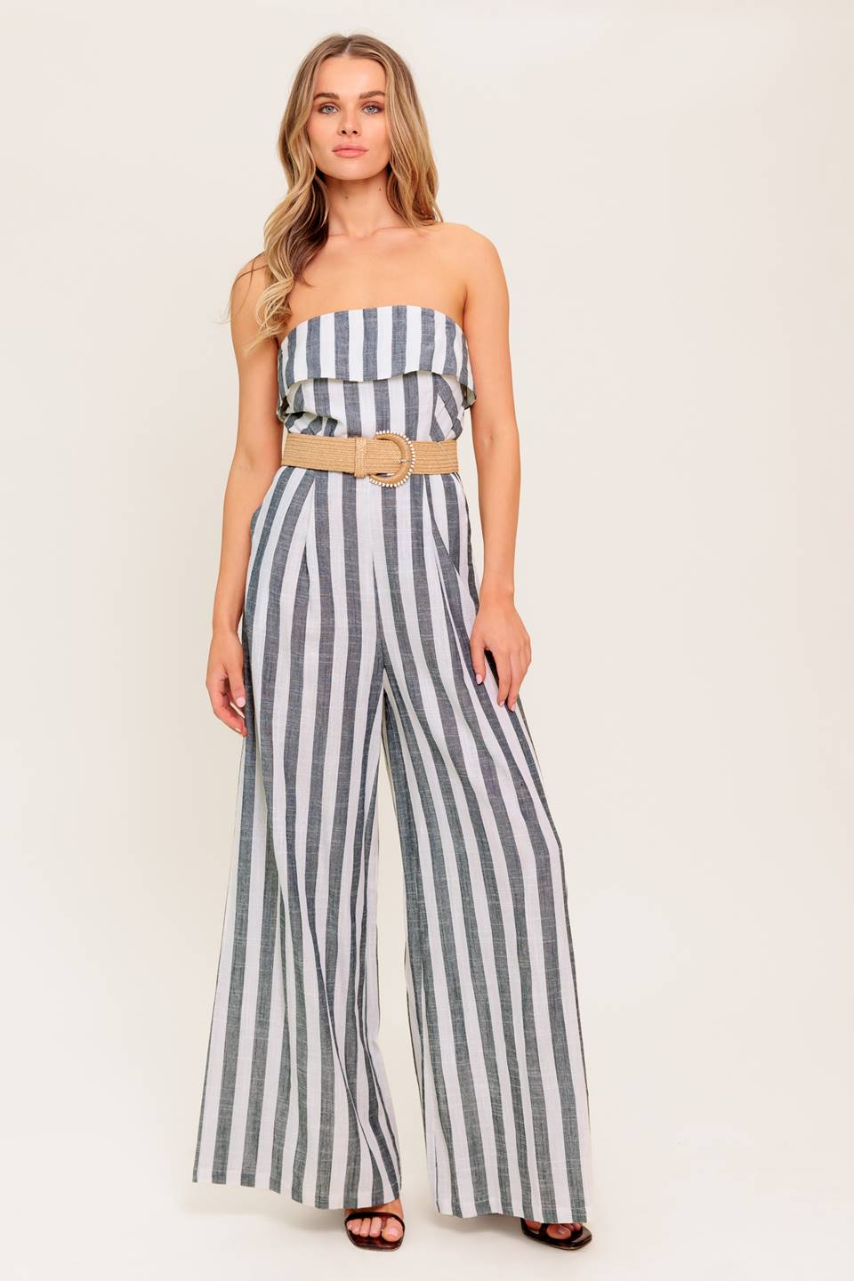 A strapless, striped woven jumpsuit featuring flounce, belt, side pockets and wide leg.