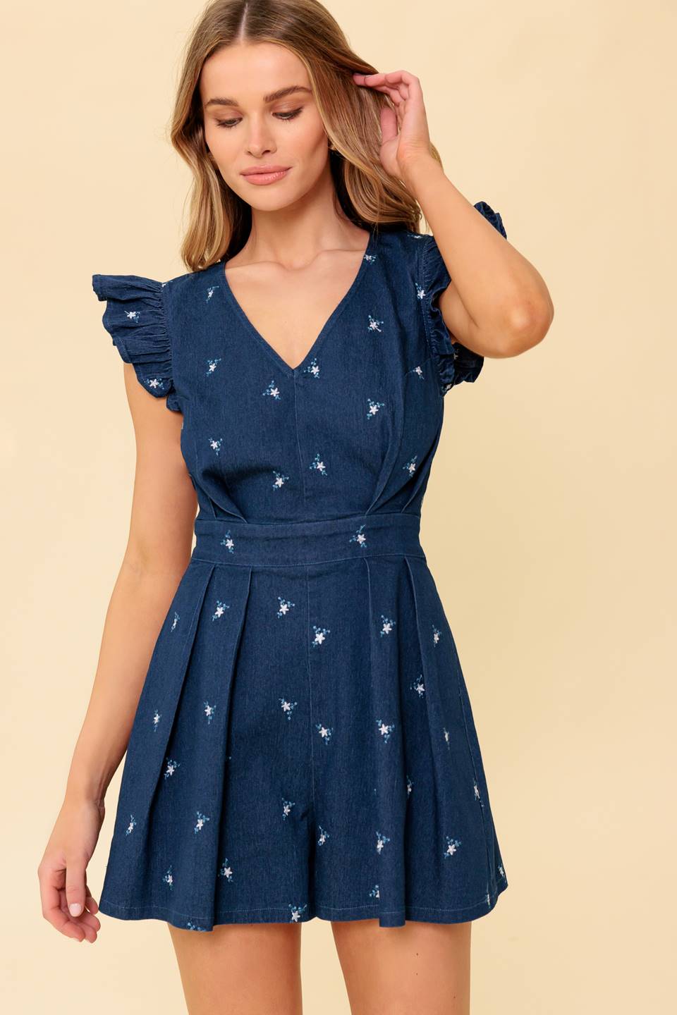 A solid embroidered denim woven romper featuring V neckline, ruffle sleeve and back zipper closure