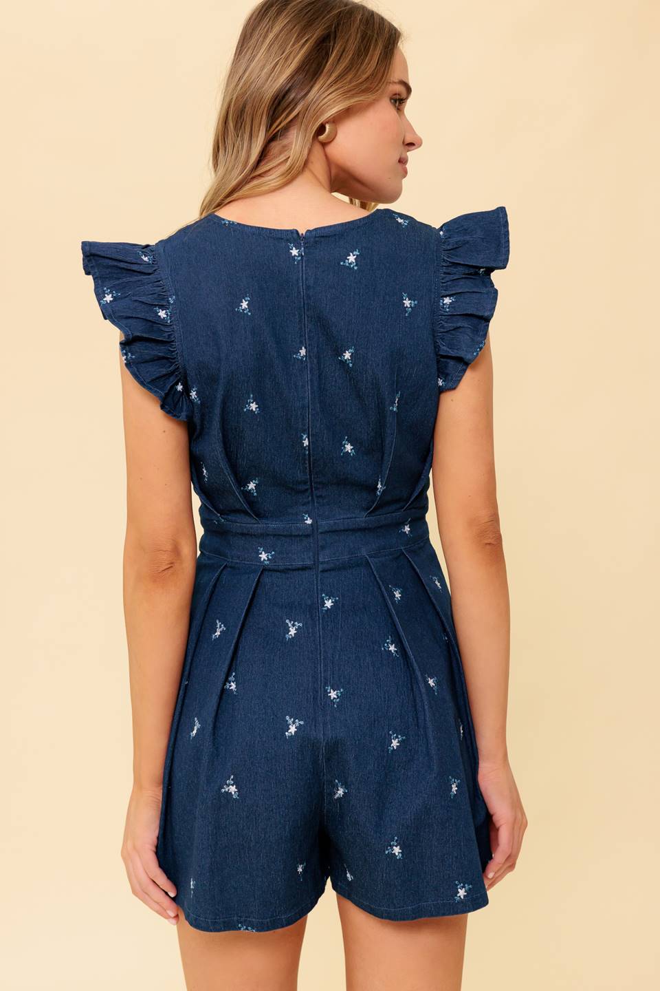 A solid embroidered denim woven romper featuring V neckline, ruffle sleeve and back zipper closure
