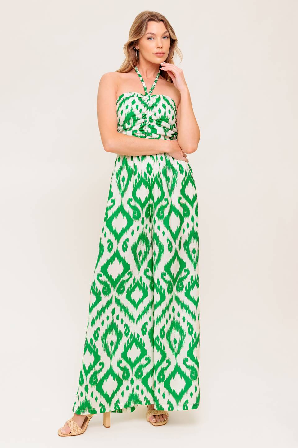 A printed woven jumpsuit featuring braided halter neckline, shirred bodice, wide leg and smocked back bodice