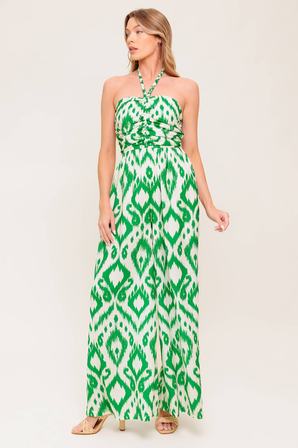 A printed woven jumpsuit featuring braided halter neckline, shirred bodice, wide leg and smocked back bodice