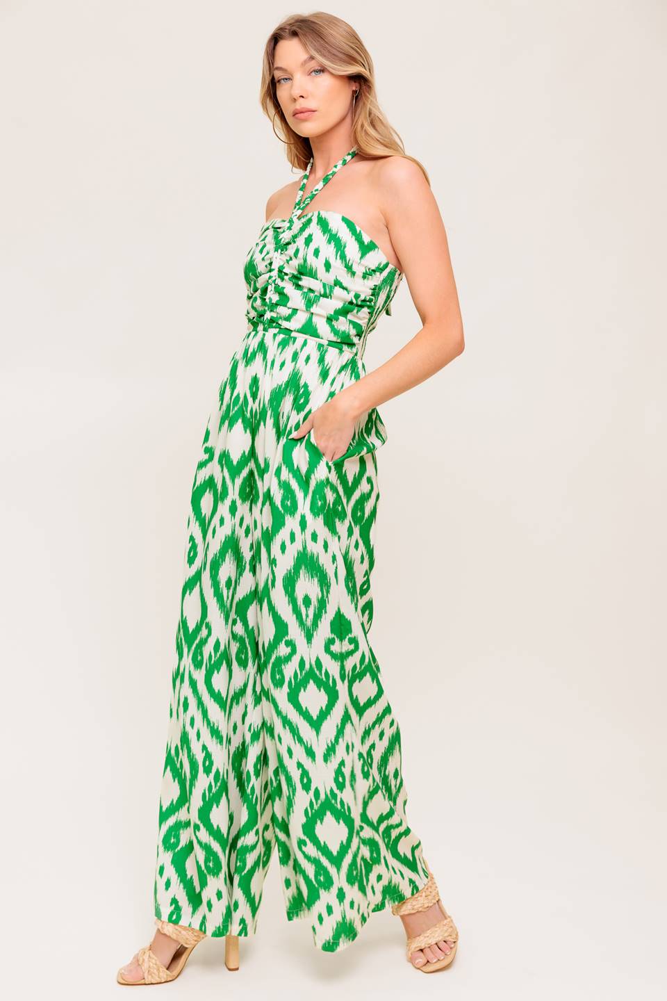 A printed woven jumpsuit featuring braided halter neckline, shirred bodice, wide leg and smocked back bodice