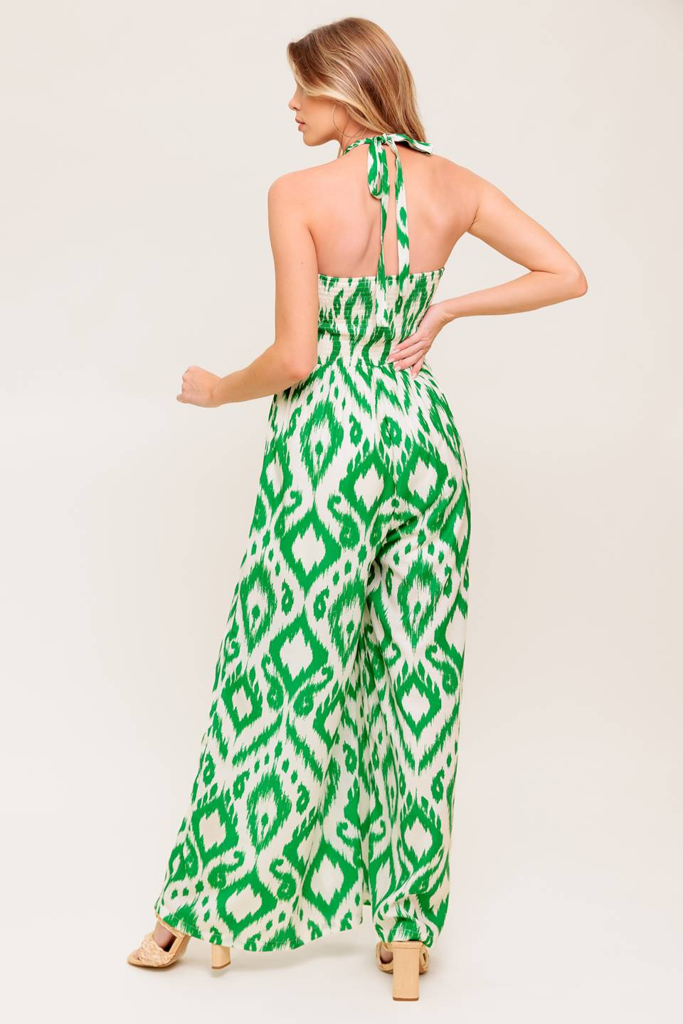 A printed woven jumpsuit featuring braided halter neckline, shirred bodice, wide leg and smocked back bodice