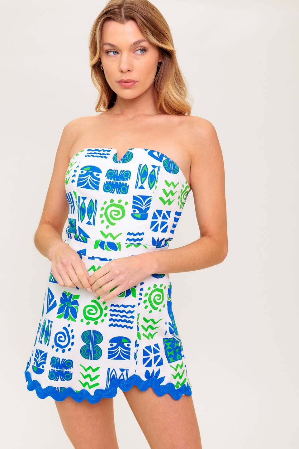 A strapless, printed woven romper featuring V center front, ric rac trimmed hem, skort bottom and back zipper closure