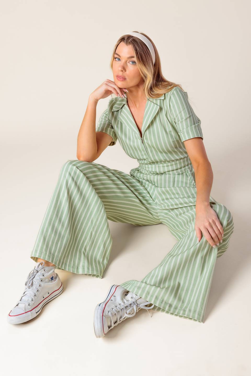 A striped woven jumpsuit featuring collar, short sleeve, zipper down front, side pocket with braided trim and wide leg