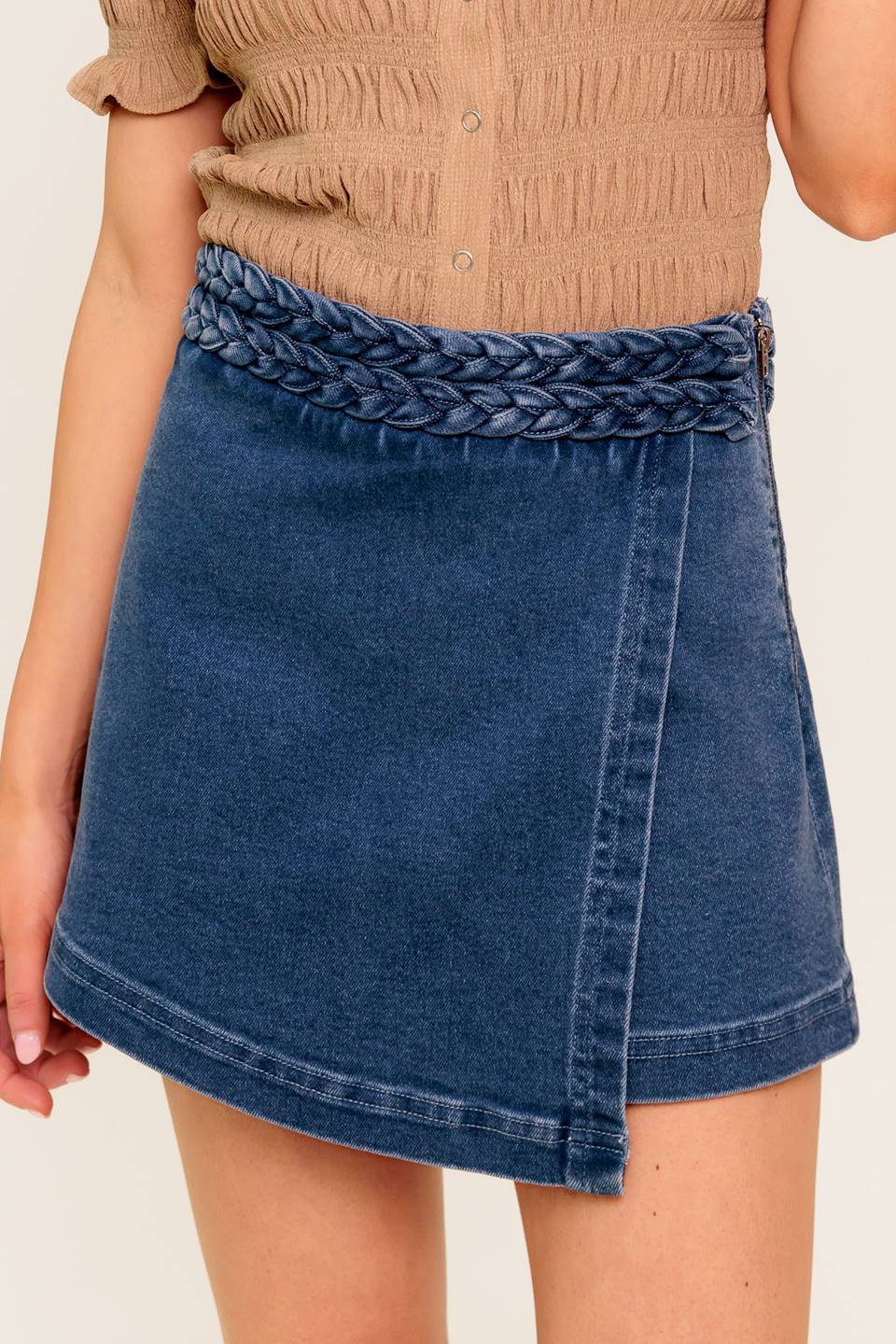 A washed denim skort featuring braided waist band and side zipper closure.