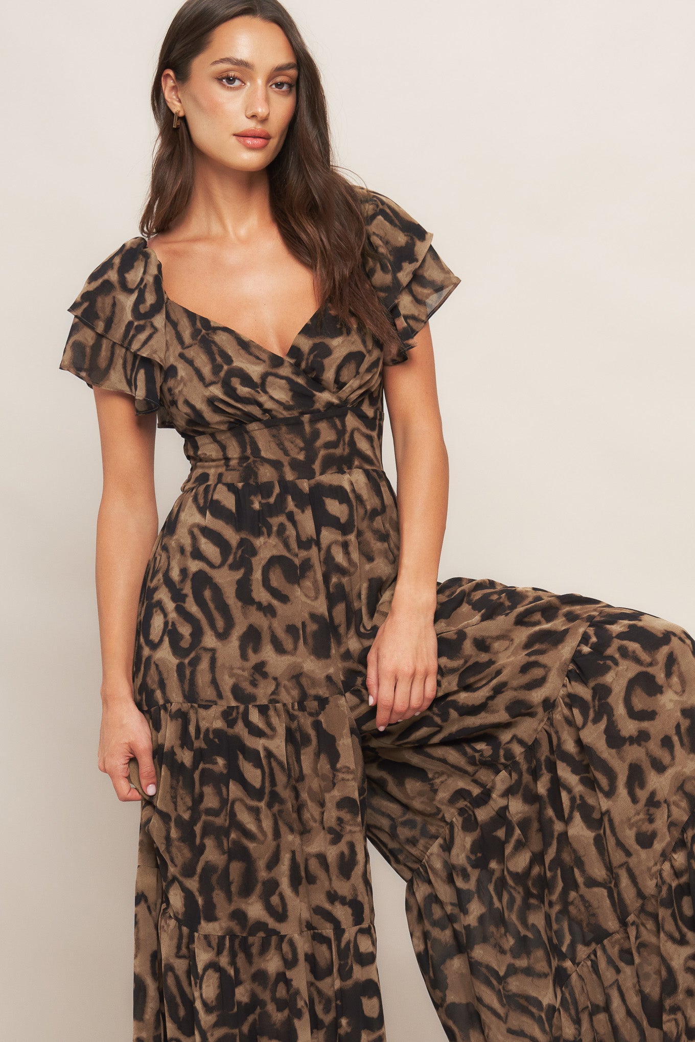 A printed woven jumpsuit featuring surplus neckline, double layered short sleeve, wide waistband tiered pant and smocked back bodice
