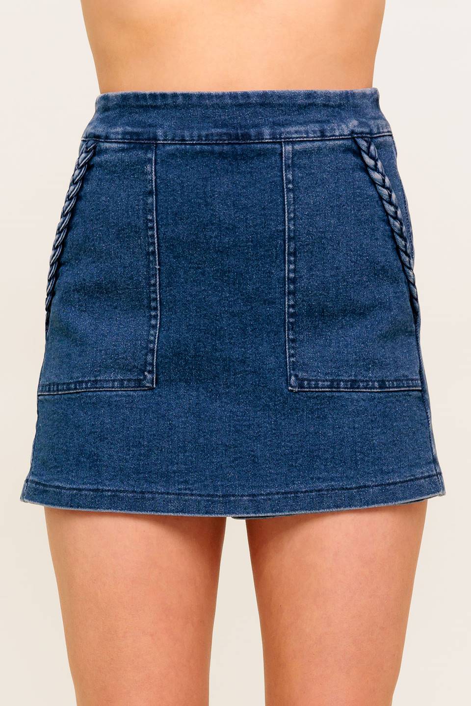 A washed denim skort featuring side pocket with braid trim and back zipper closure.
