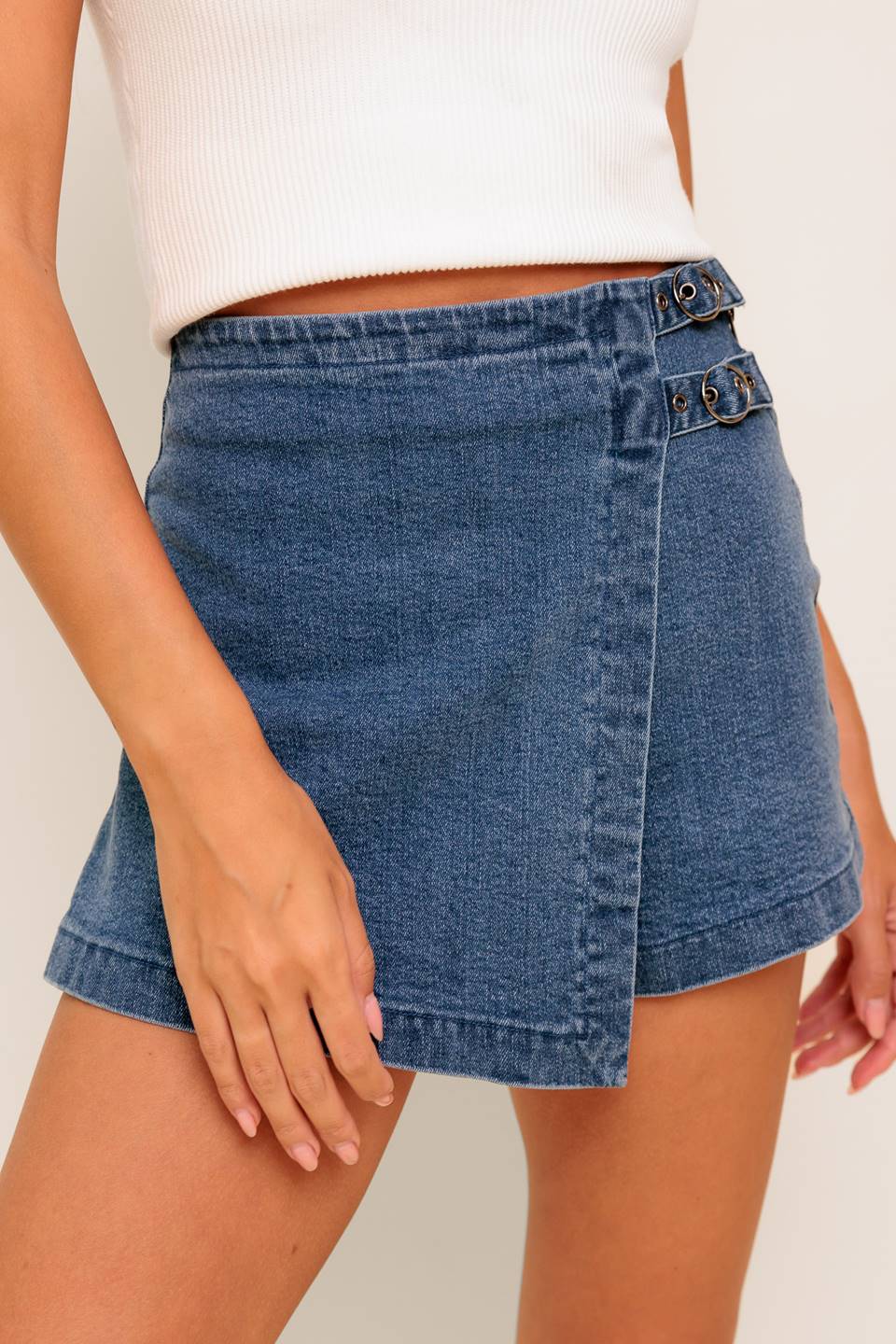 A washed denim skort featuring side buckle detail and zipper closure.