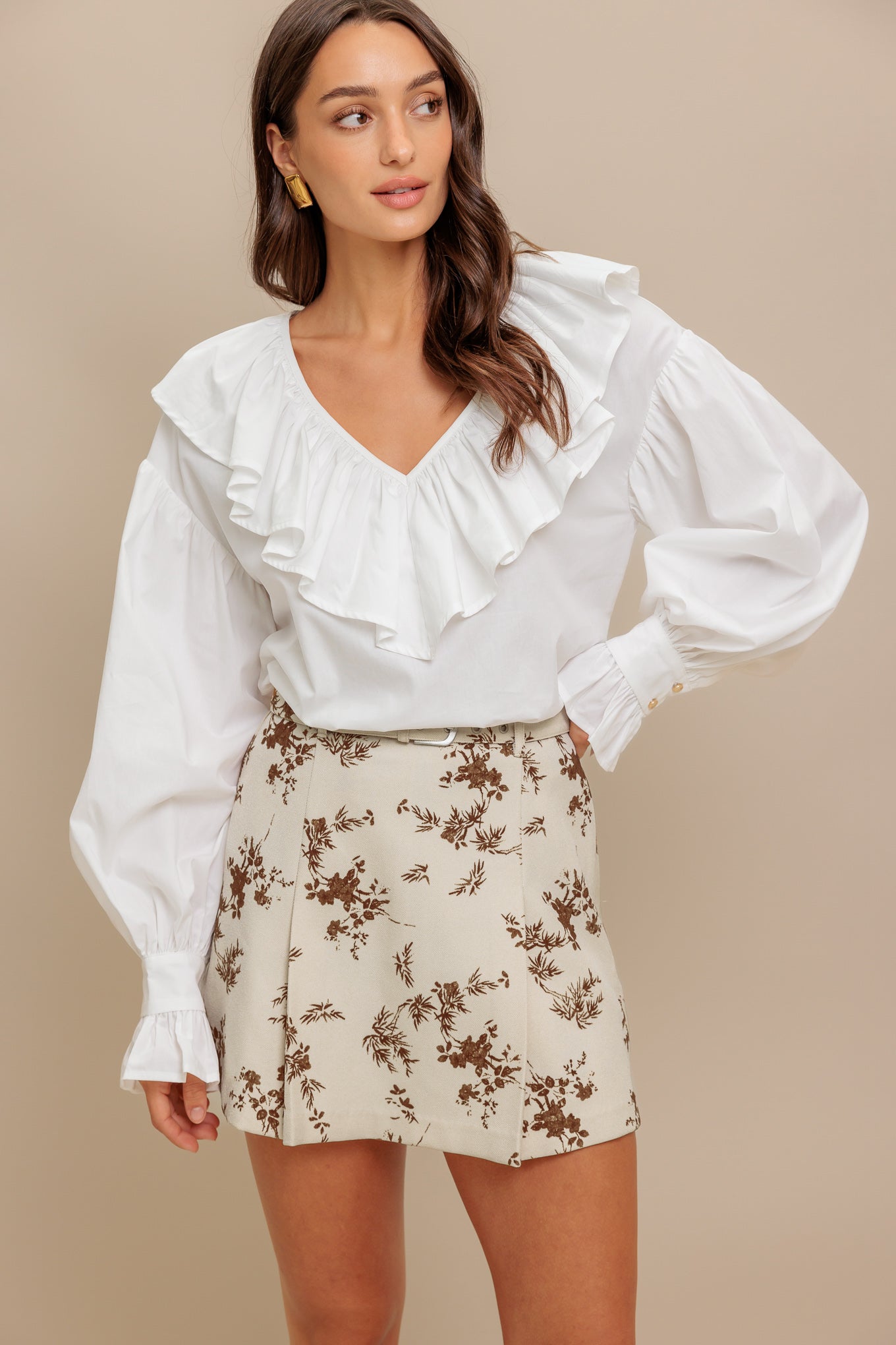 A cream and floral printed woven skort with self belt and side zipper closure